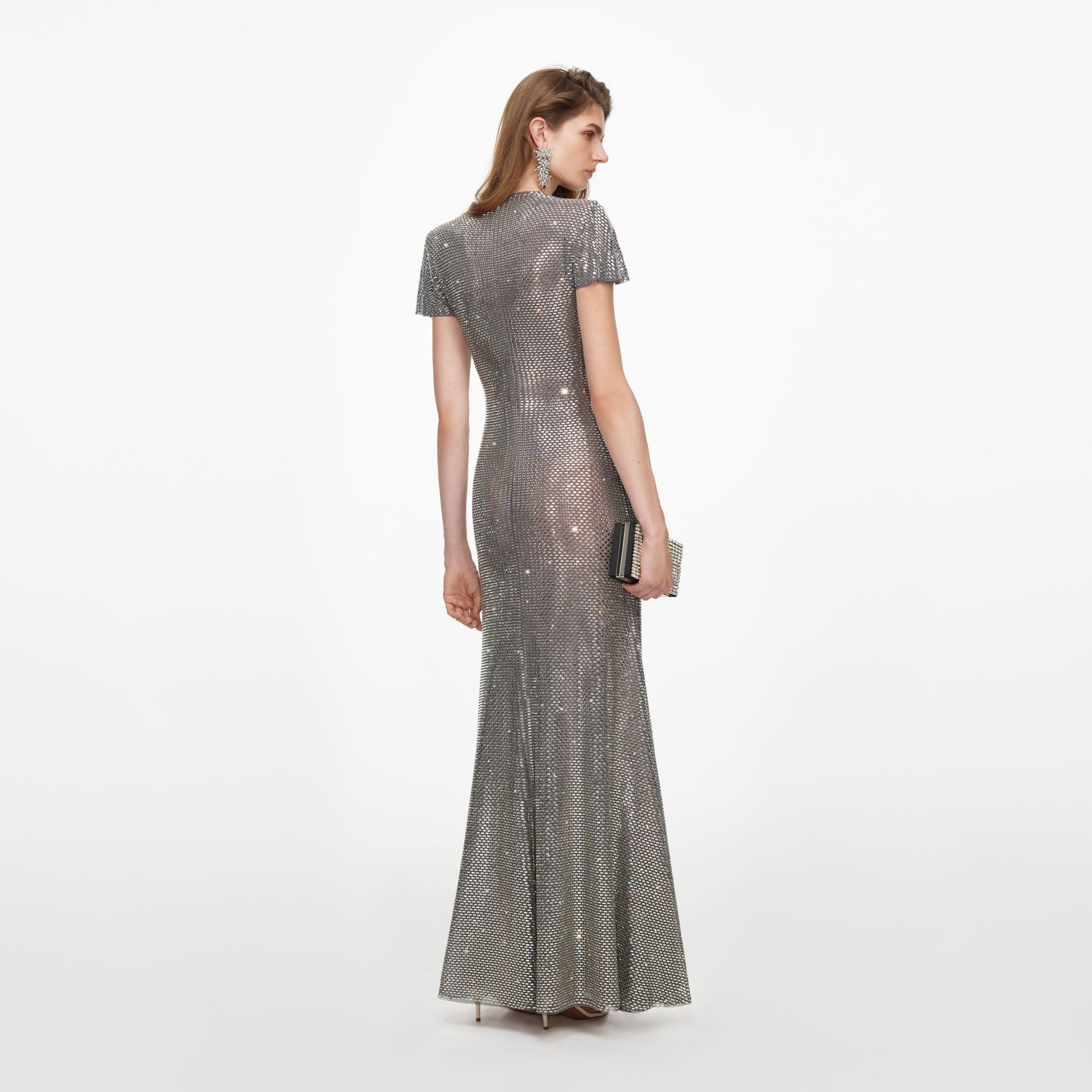 Woman in a silver sequined gown with short sleeves and a clutch bag
