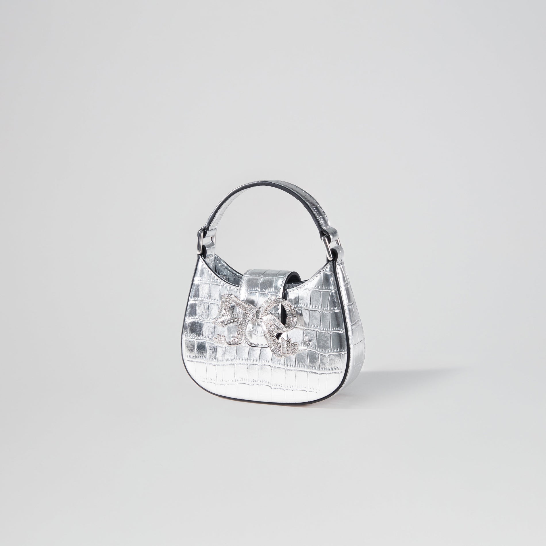 Side view of a woman wearing the Silver Croc Crescent Bow Micro Bag