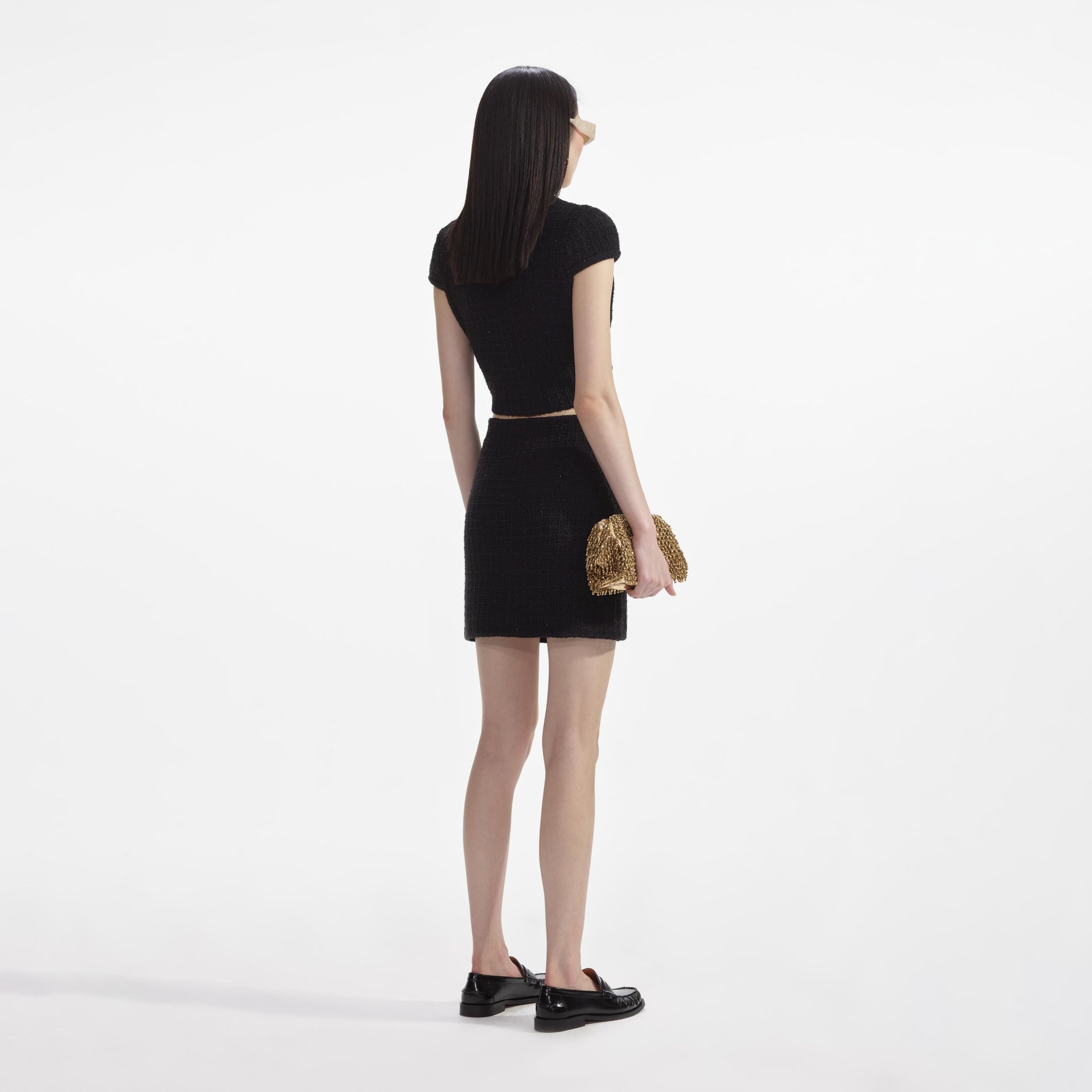 Back view of a woman wearing the Black Jewel Button Knit Mini Skirt
