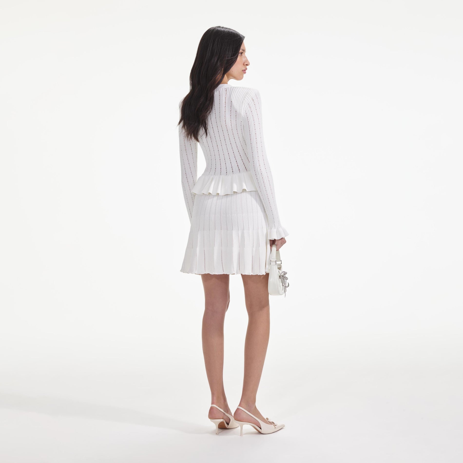Back view of a woman wearing the White Knit Peplum Mini Dress
