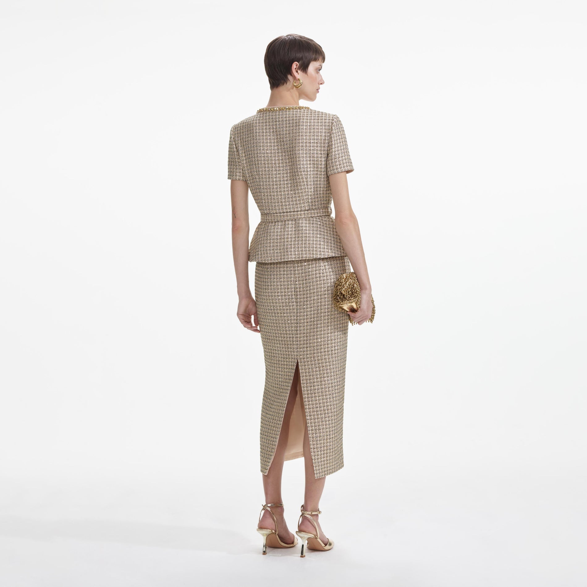 Back view of a woman wearing the Gold Boucle Peplum Top