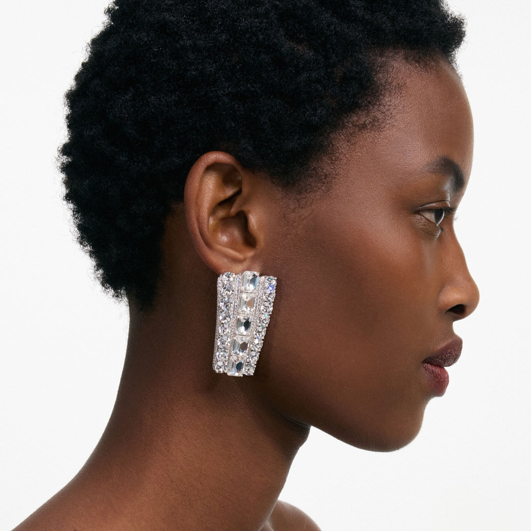 Close up of a woman's face in profile, wearing a large rectangular crystal earring