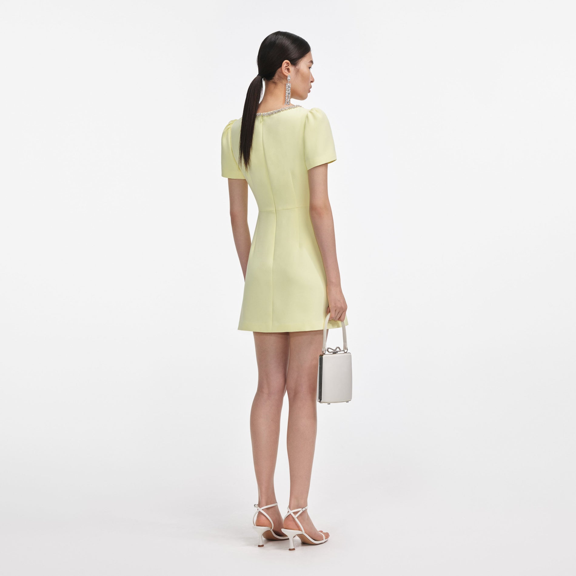 Back view of a woman wearing the Yellow Crepe Crystal Trim Mini Dress
