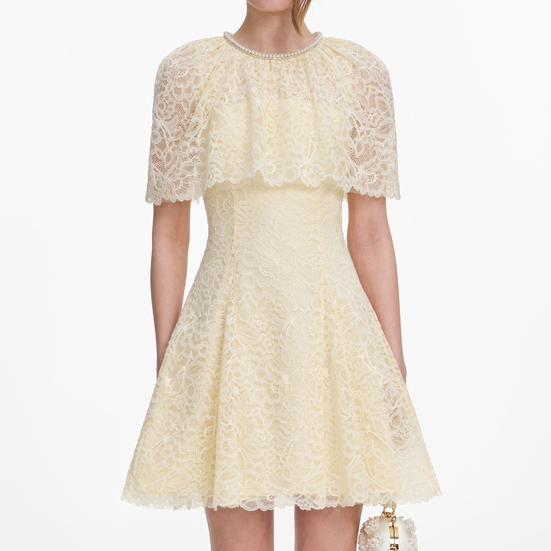 A close up of a woman wearing the Yellow Lace Cape Mini Dress