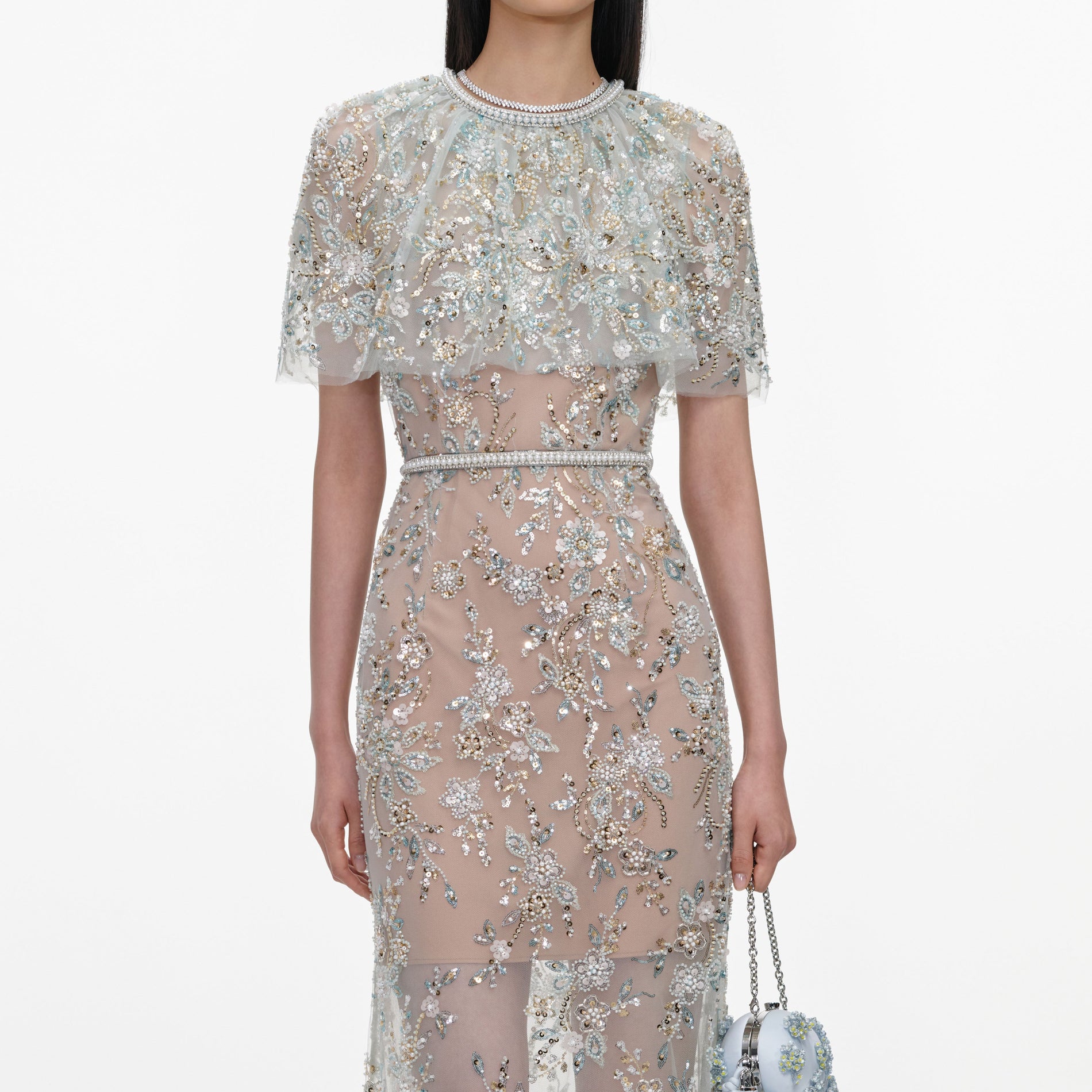 A close up of a woman wearing the Mint Embellished Cape Maxi Dress