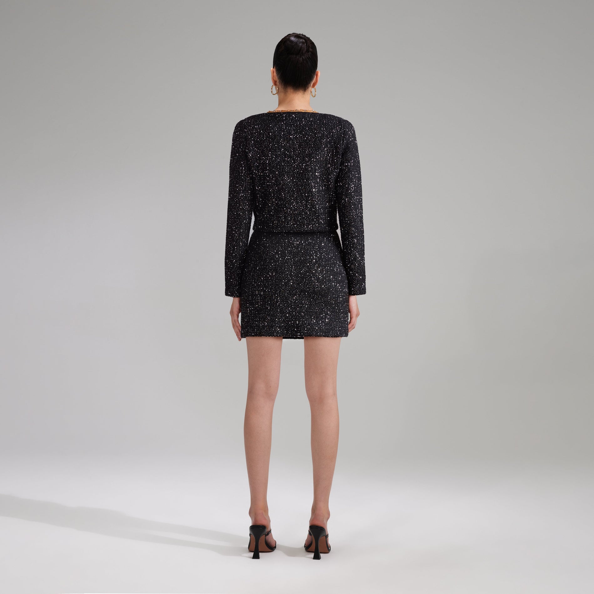 A woman wearing the Black Sequin Knit Mini Skirt