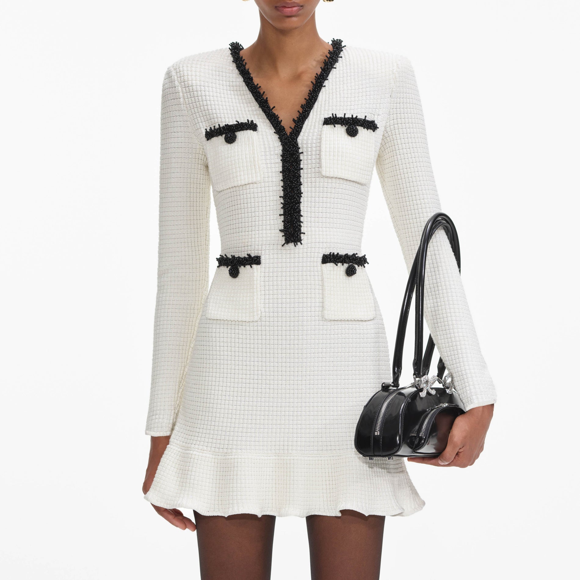 A close up of a woman wearing the White Pearl Trim Knit Mini Dress