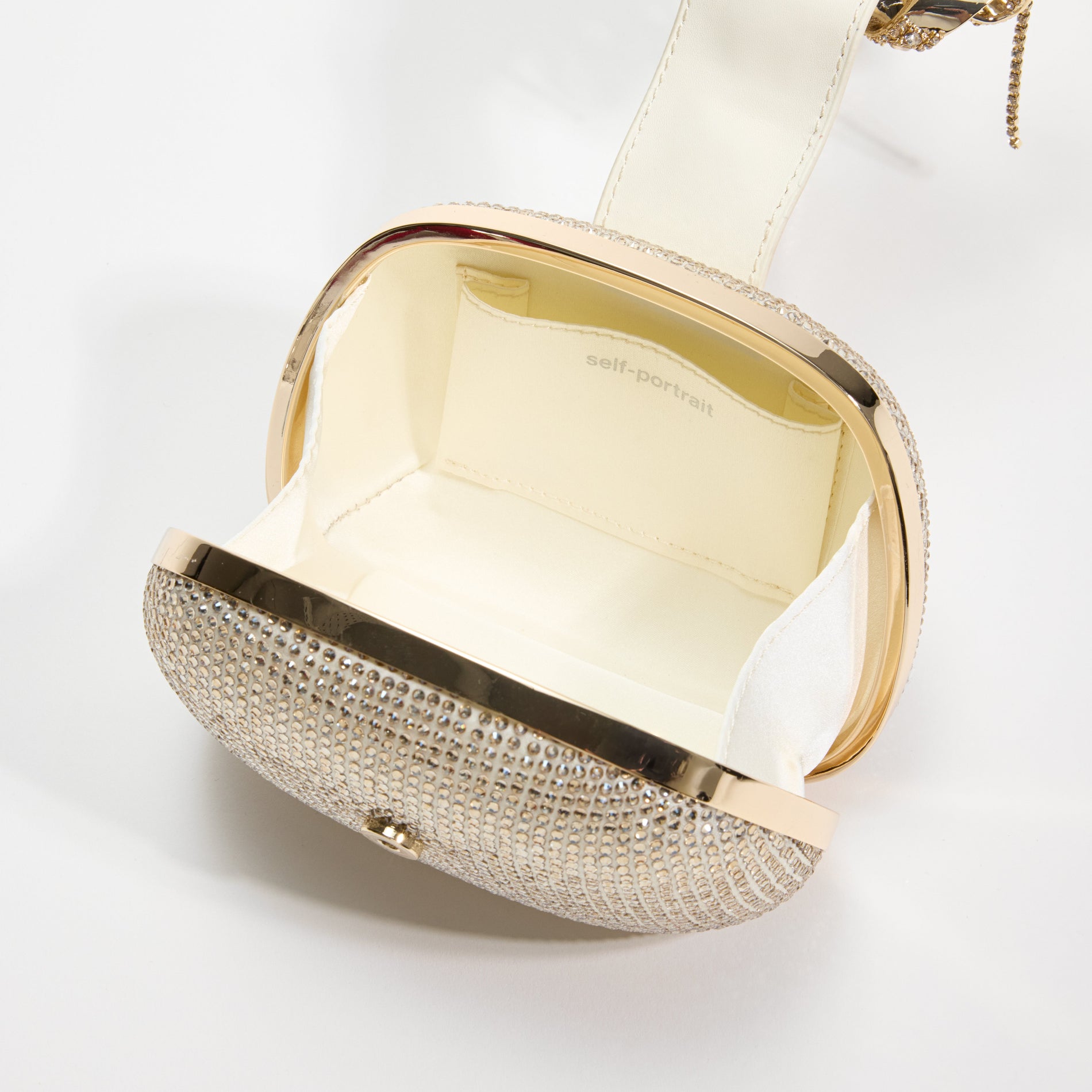 A close up of a woman wearing the Champagne Rhinestone Top Handle Clutch Bag
