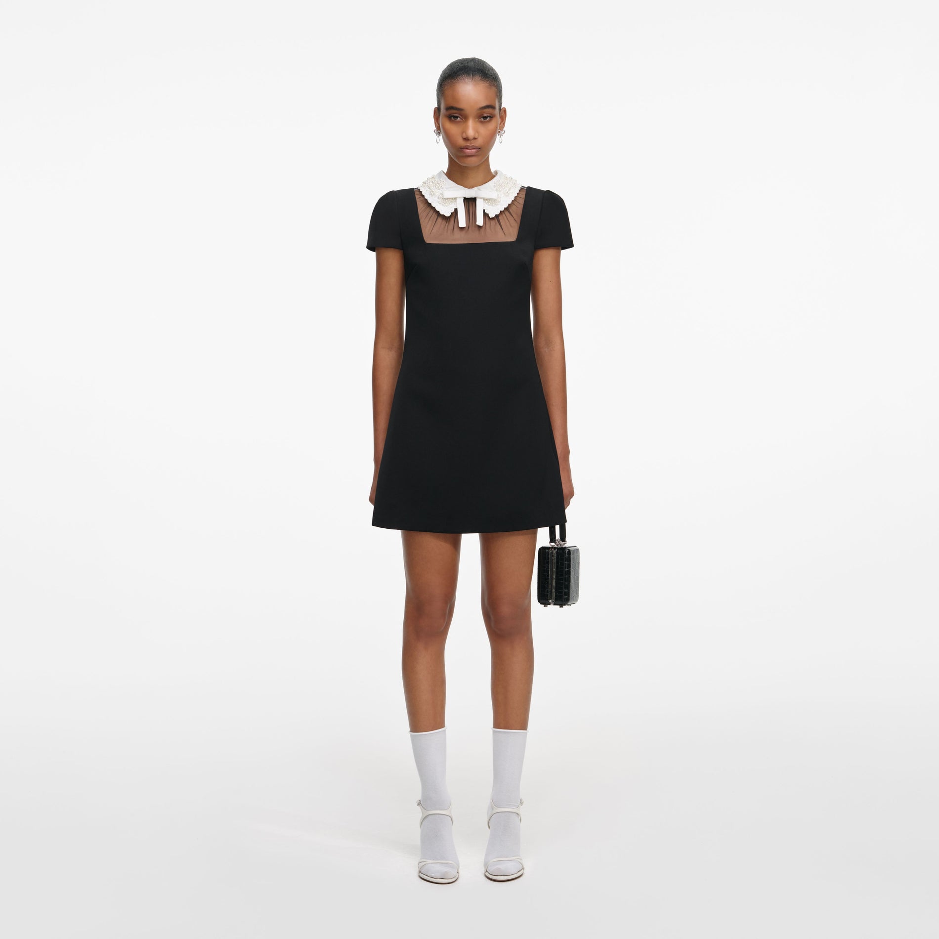 Front view of a woman wearing the Black Crepe Bow Collar Mini Dress