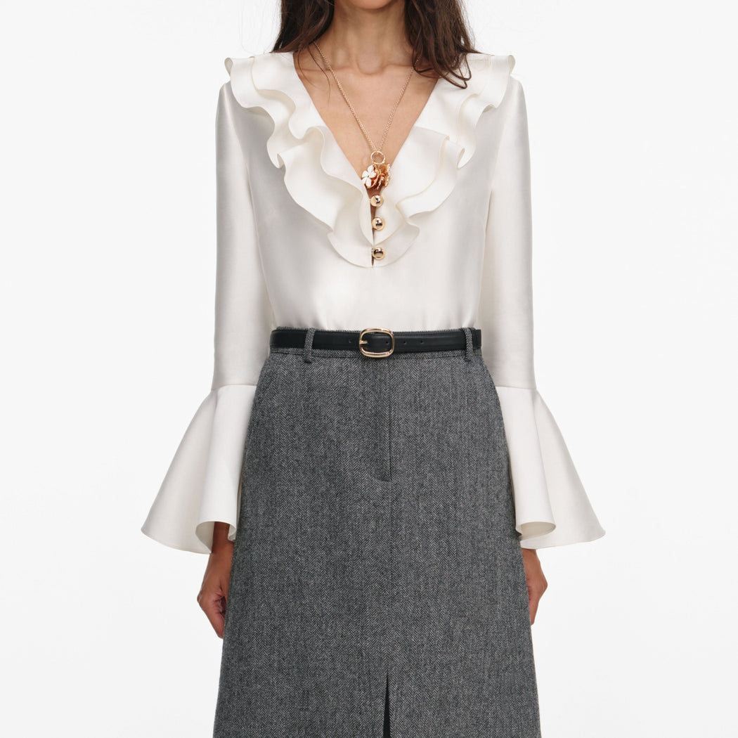 A close up of a woman wearing the Cream Taffeta Ruffle Top