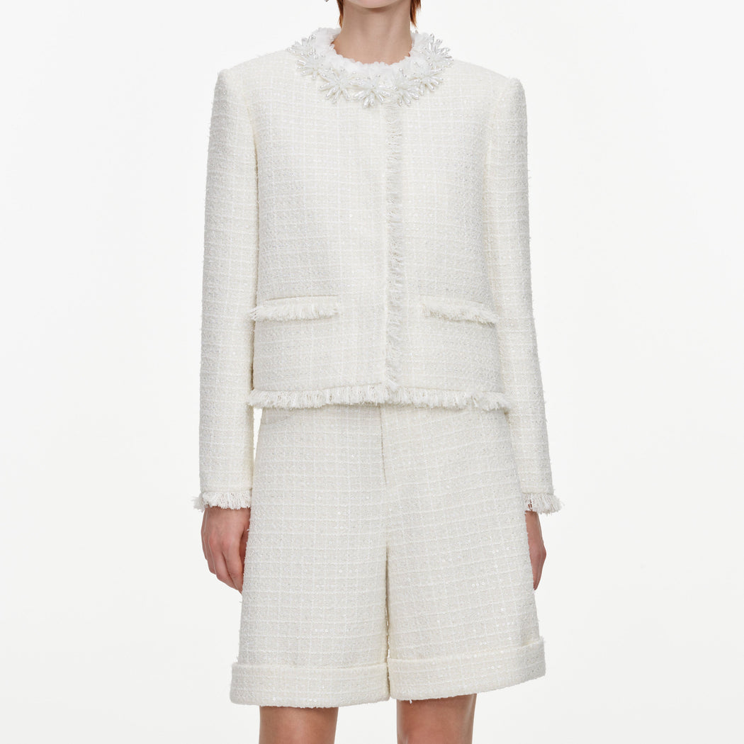 A close up of a woman wearing the Cream Sequin Boucle Pearl Trim Jacket
