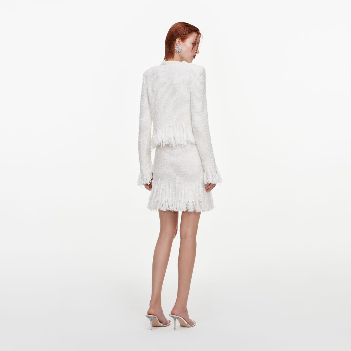 Back view of a woman wearing the White Fringe Knit Mini Skirt