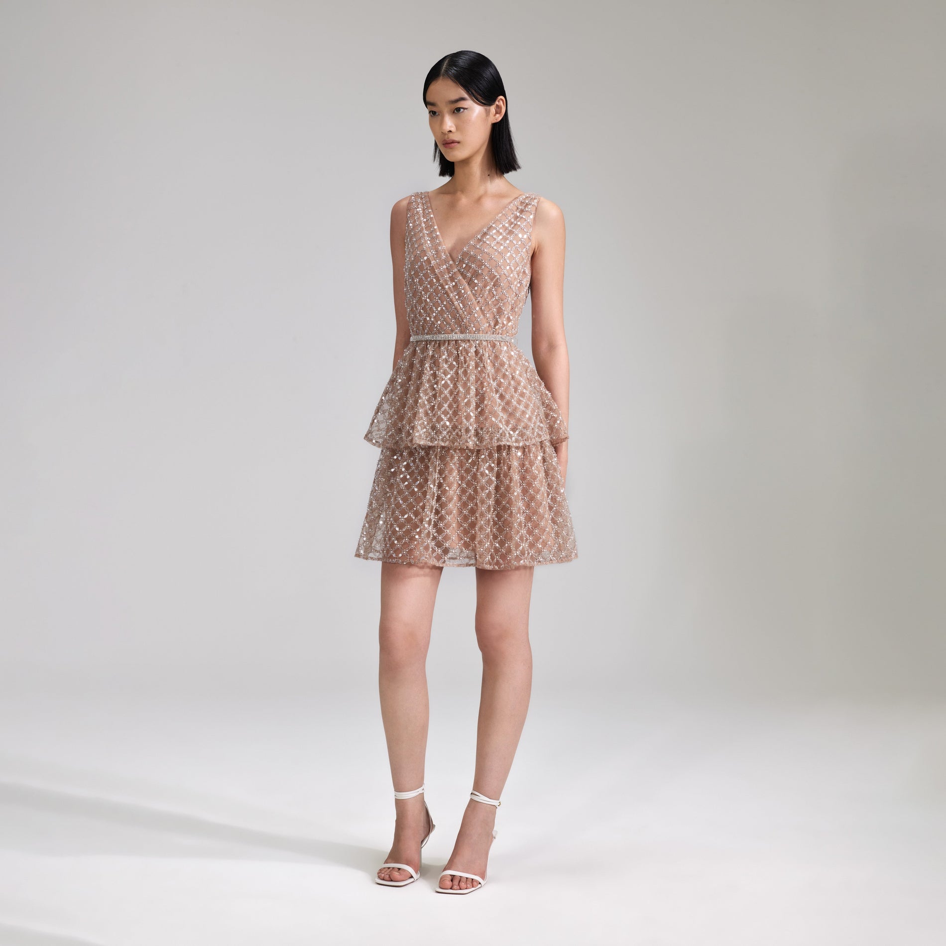 A woman wearing the Tan Grid Sequin Tiered Mini Dress