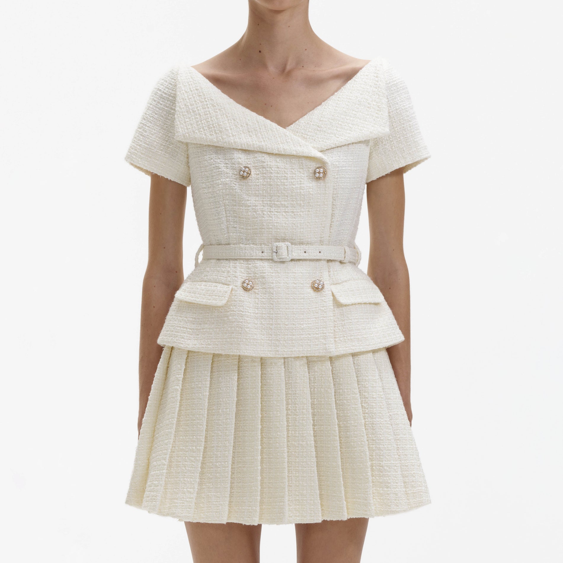 A close up of a woman wearing the Cream Boucle Pleated Mini Dress