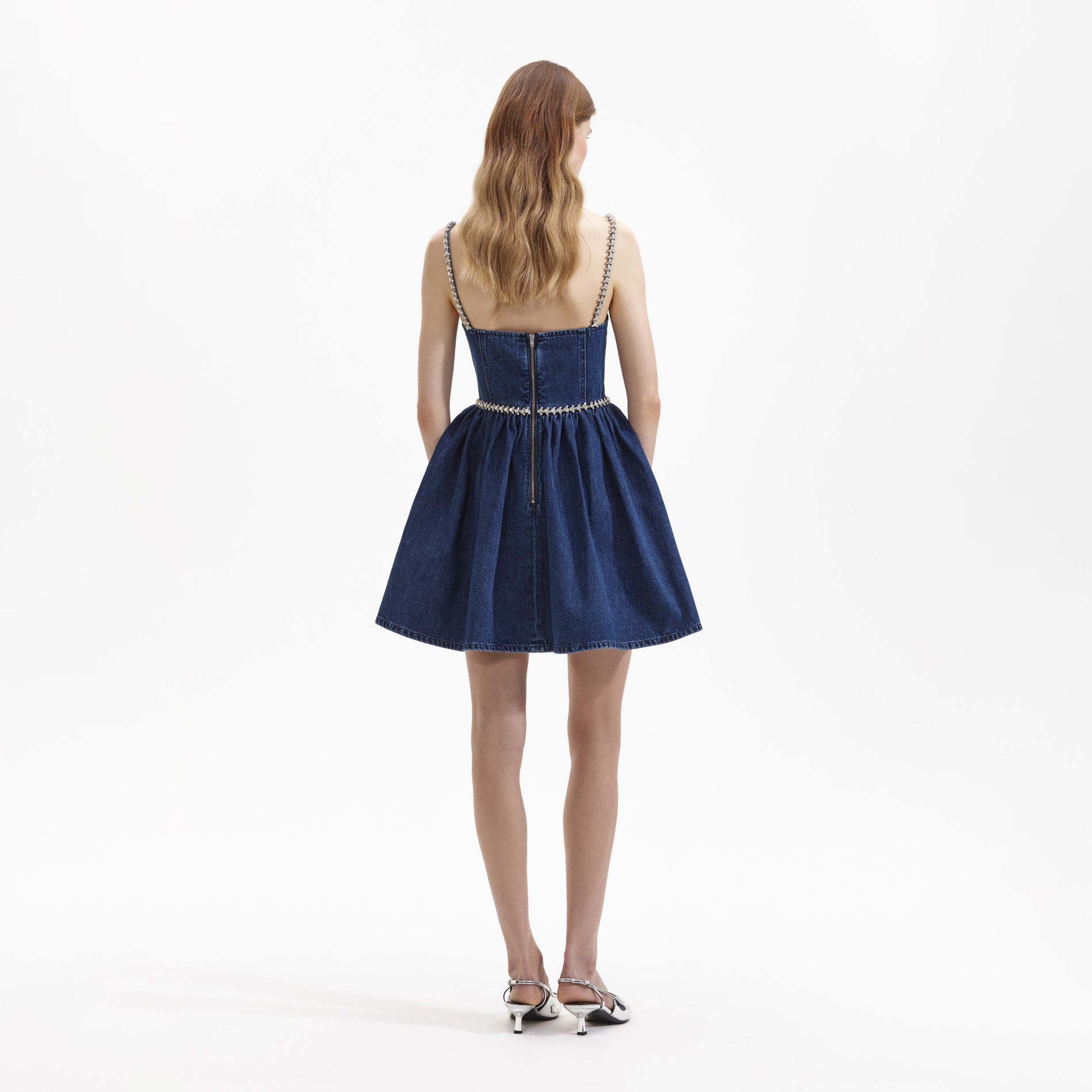 Back view of a woman wearing the Diamante Bow Denim Mini Dress