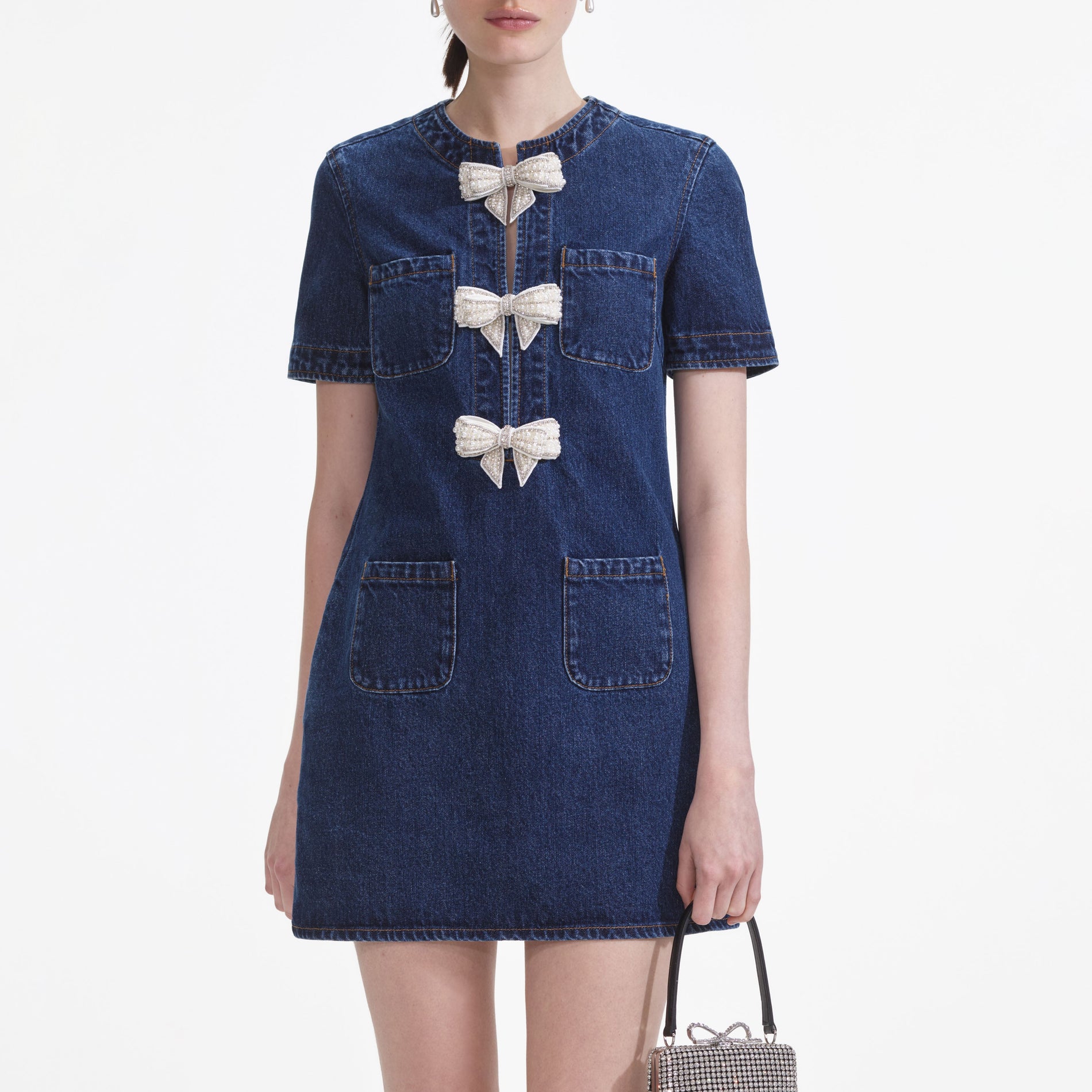 A close up of a woman wearing the Denim Bow Mini Dress