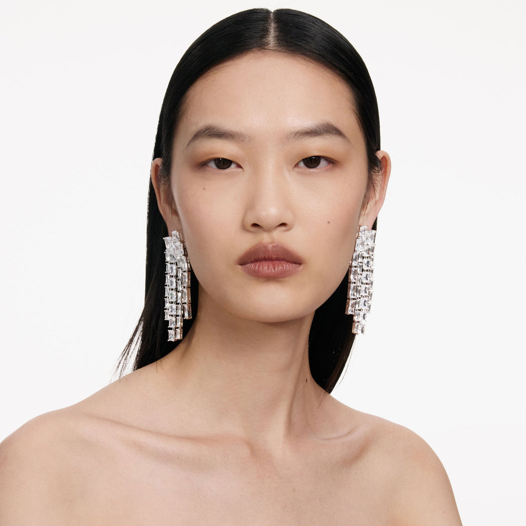 Woman with dark hair and bare shoulders wearing long, rectangular crystal drop earrings