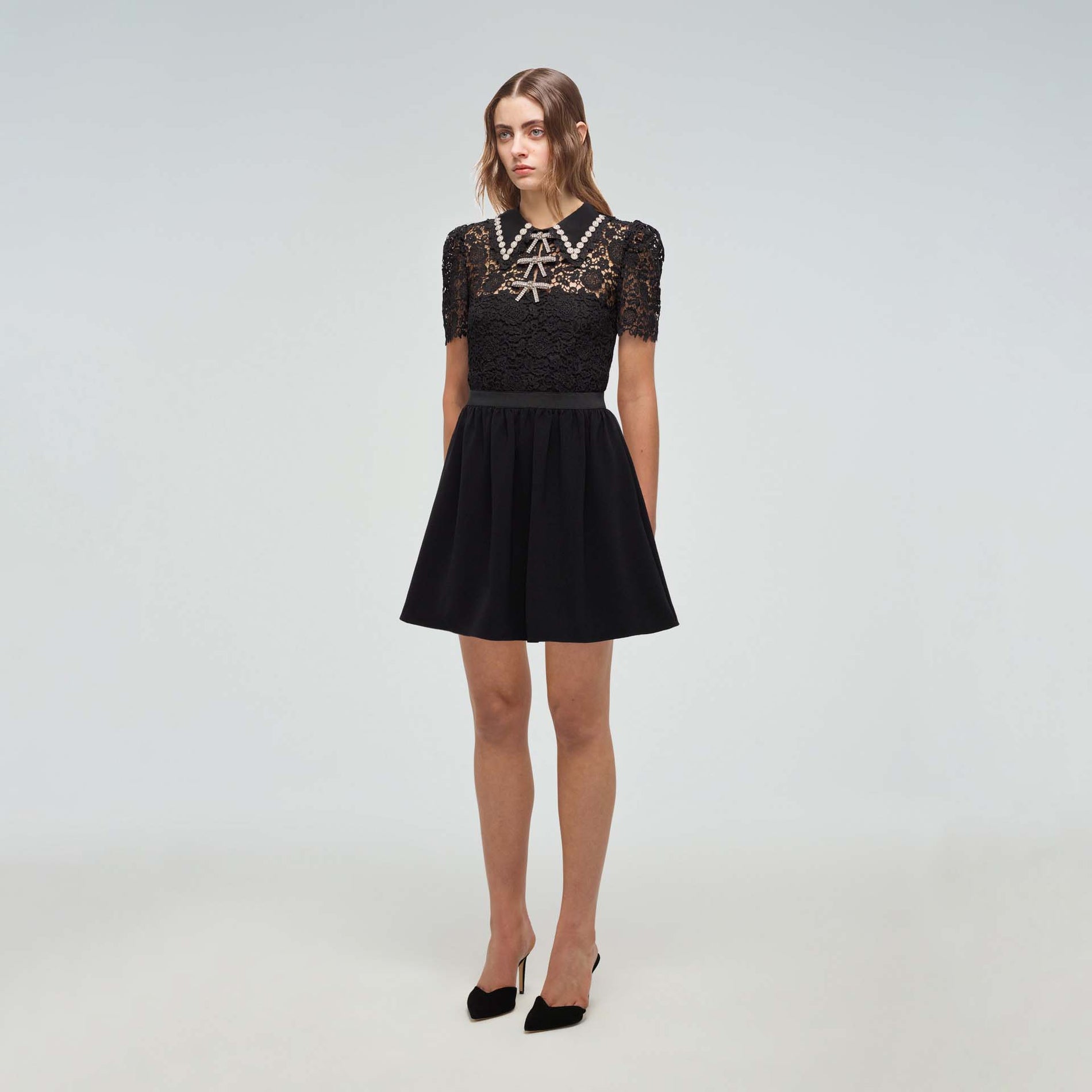A woman wearing the Black Guipure Mini Dress