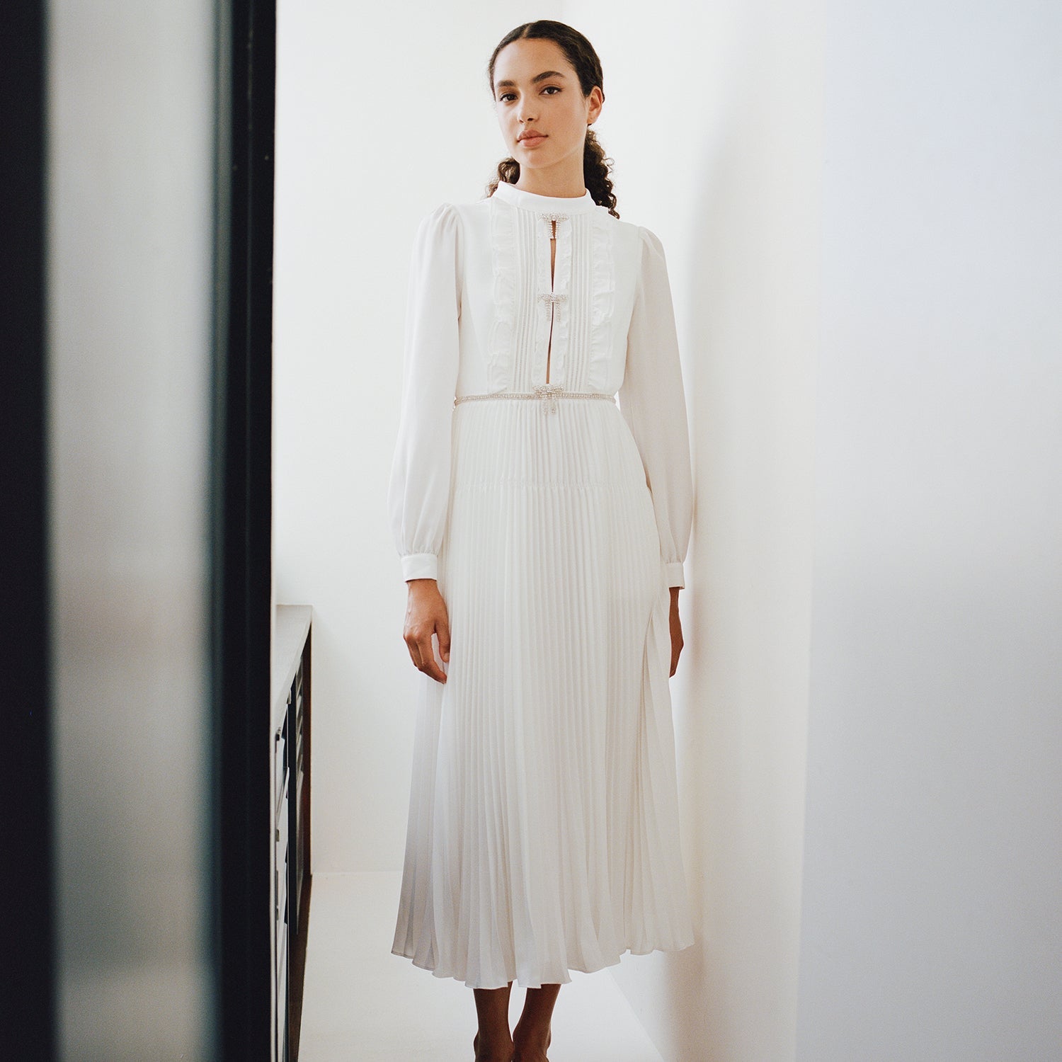 A woman wearing the Ivory Ruffled Bib Midi Dress