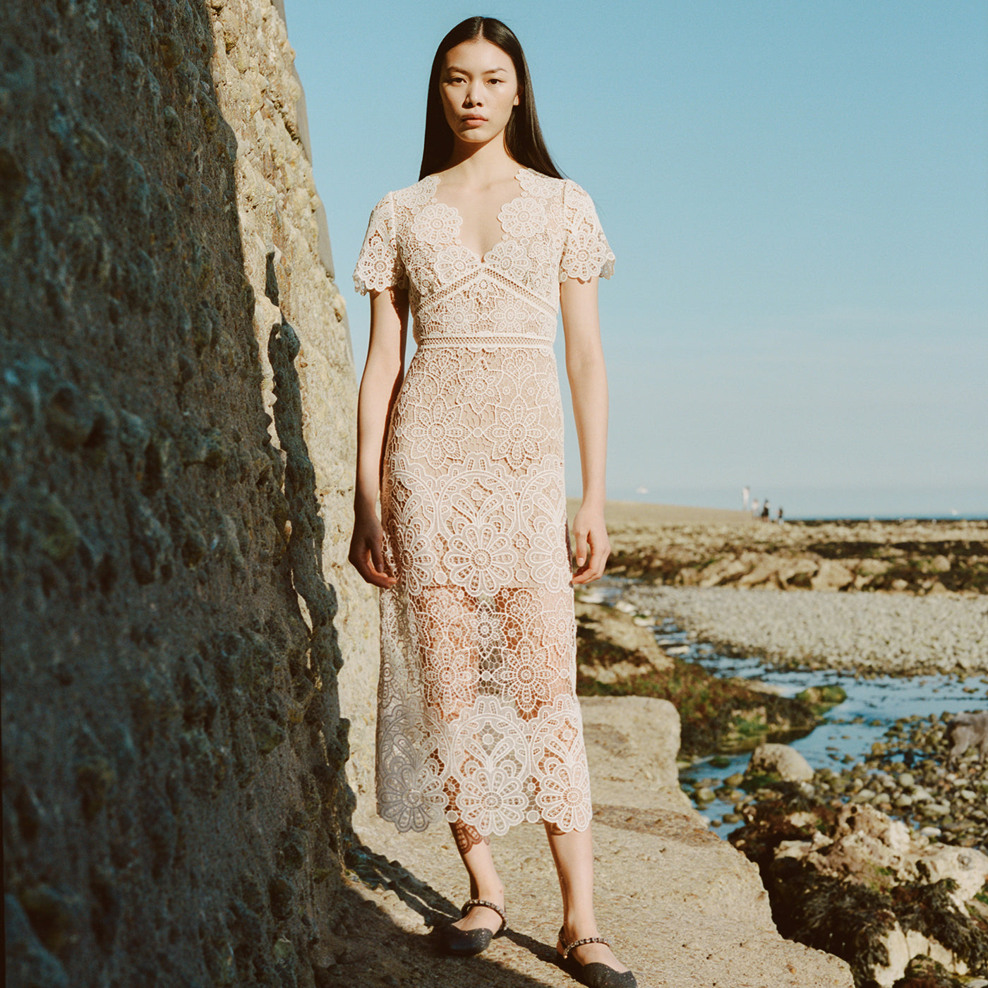 A woman wearing the Ivory Floral Guipure V-Neck Midi Dress