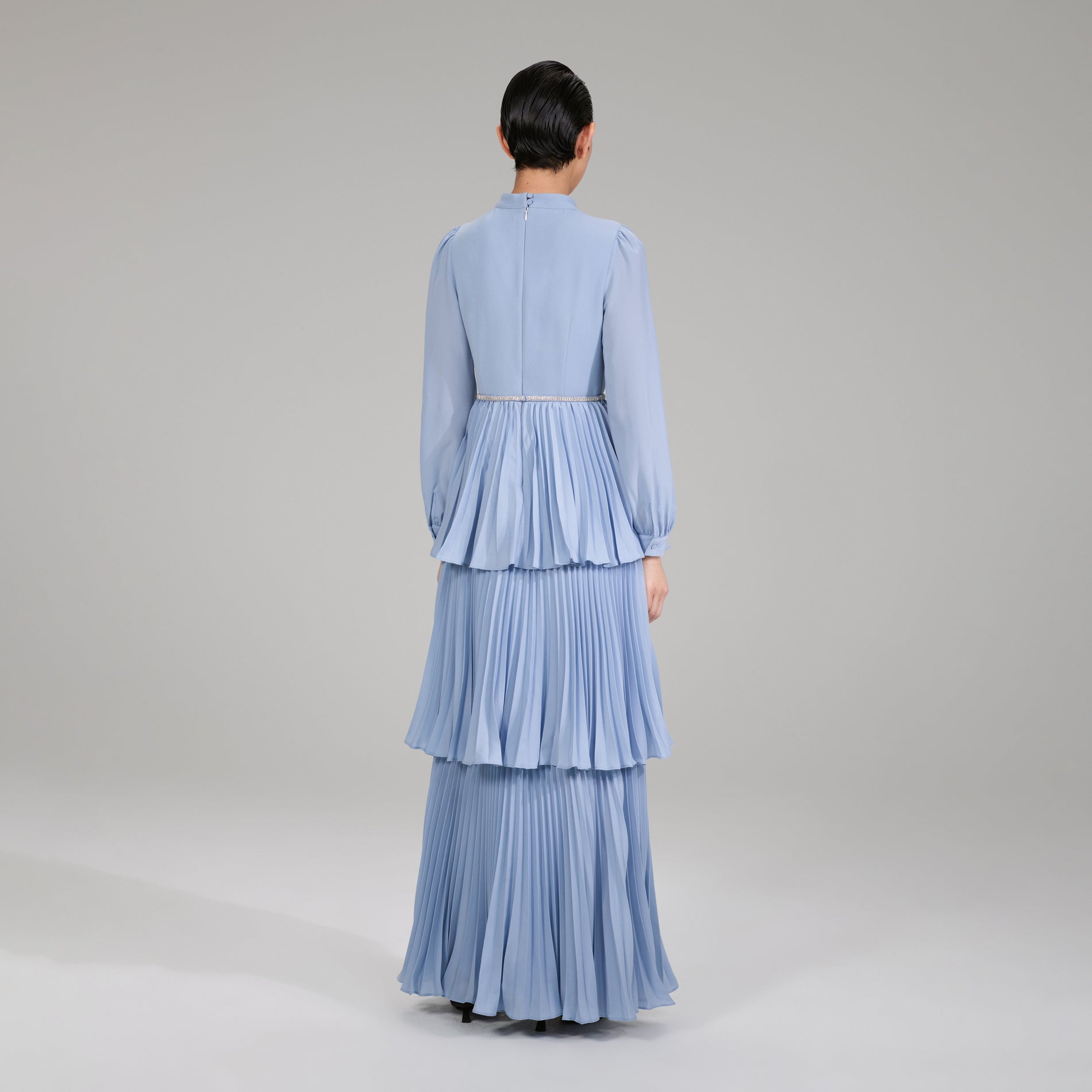 A woman wearing the Pastel Blue Ruffled Bib Maxi Dress