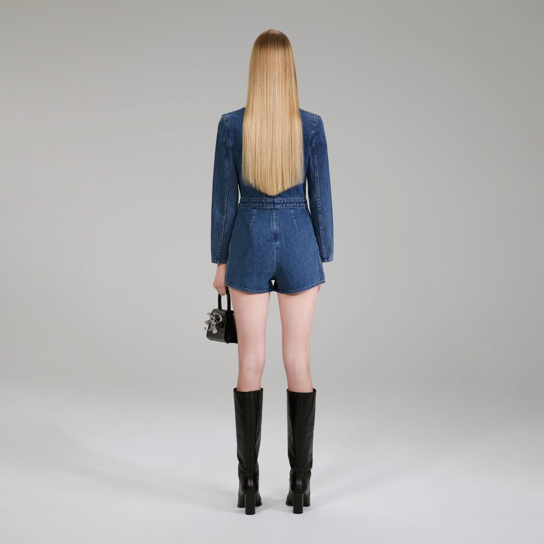 A woman wearing the Dark Wash Denim Bow Playsuit