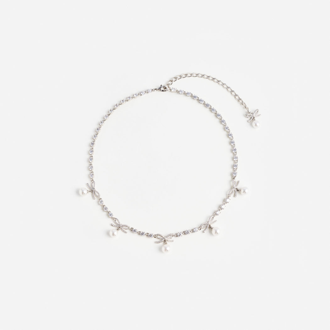 Silver necklace with small clear stones, five bow-shaped charms, and five small white pearls