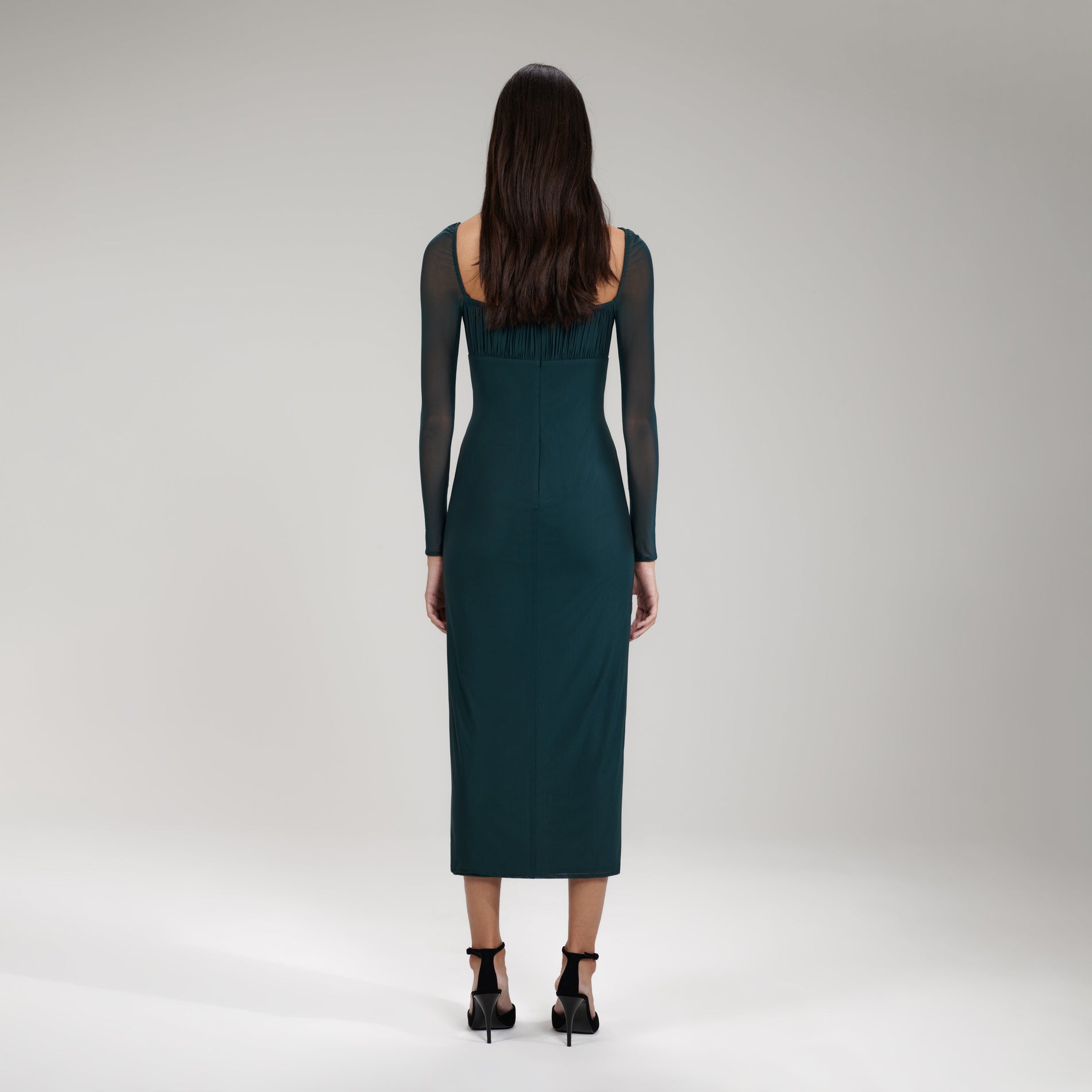 A woman wearing the Dark Green Powermesh Ruched Midi Dress