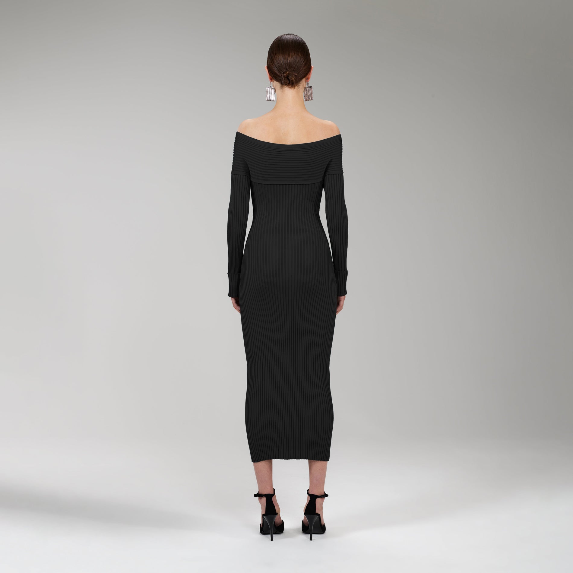 A woman wearing the Black Ribbed Knit Crossover Bust Midi Dress