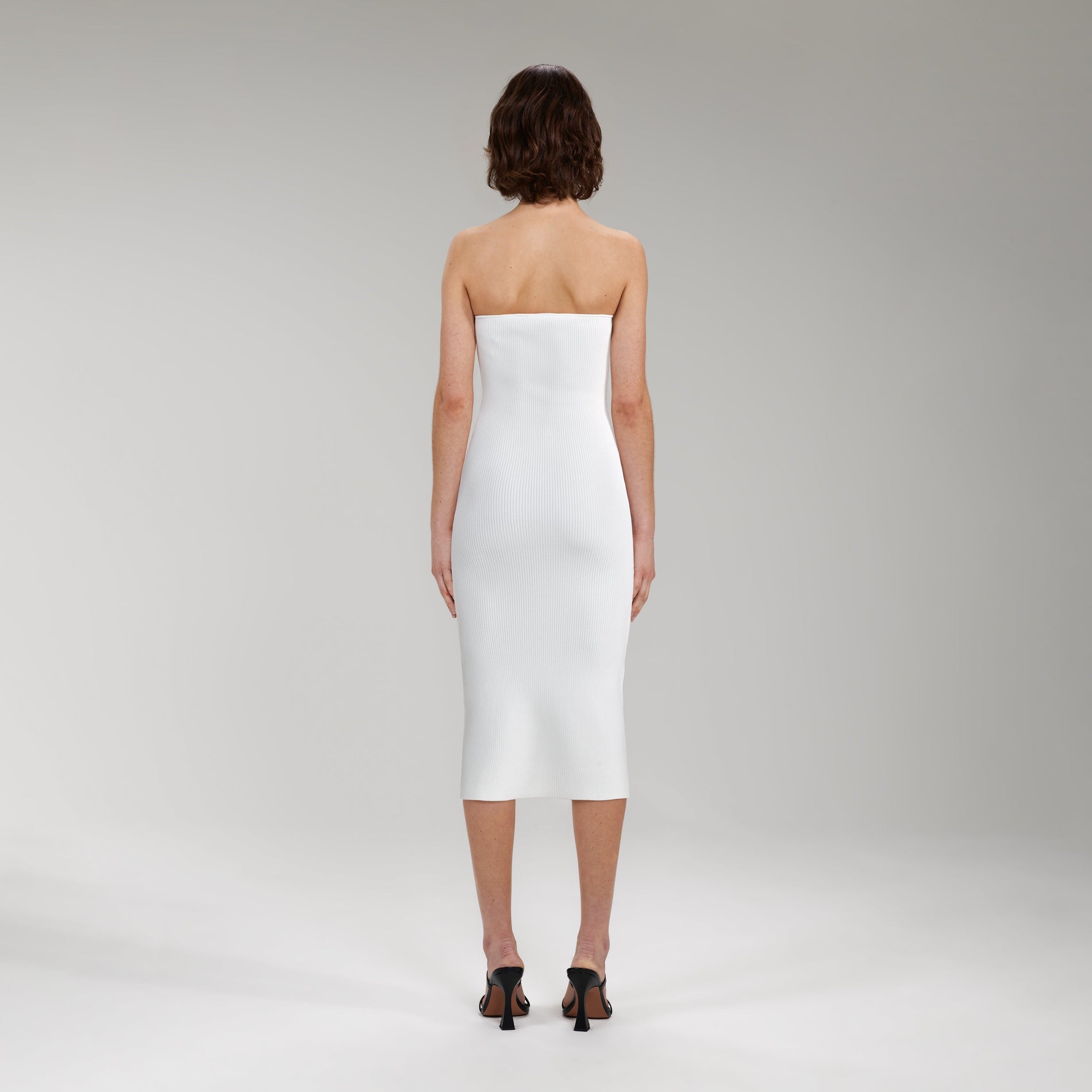 A woman wearing the White Strapless Ribbed Knit Midi Dress