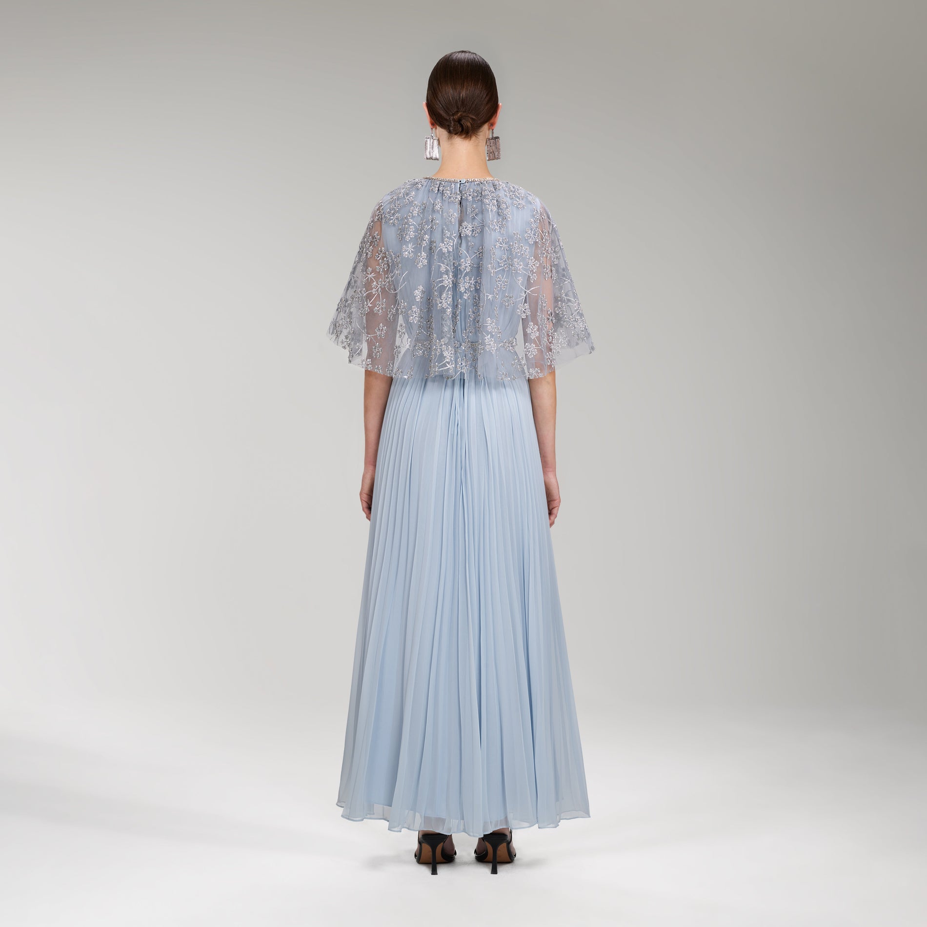 A woman wearing the Embroidered Blossom Cape Maxi Dress