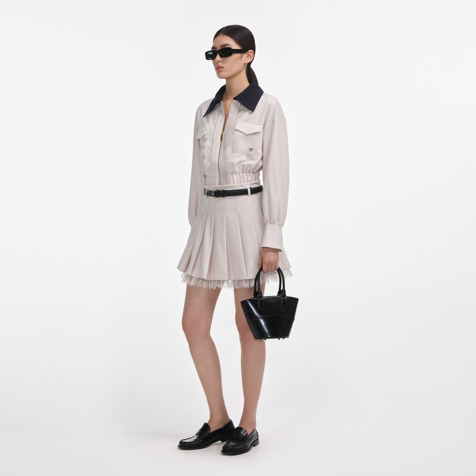 Side view of a woman wearing the Cream Twill Pleated Mini Skirt