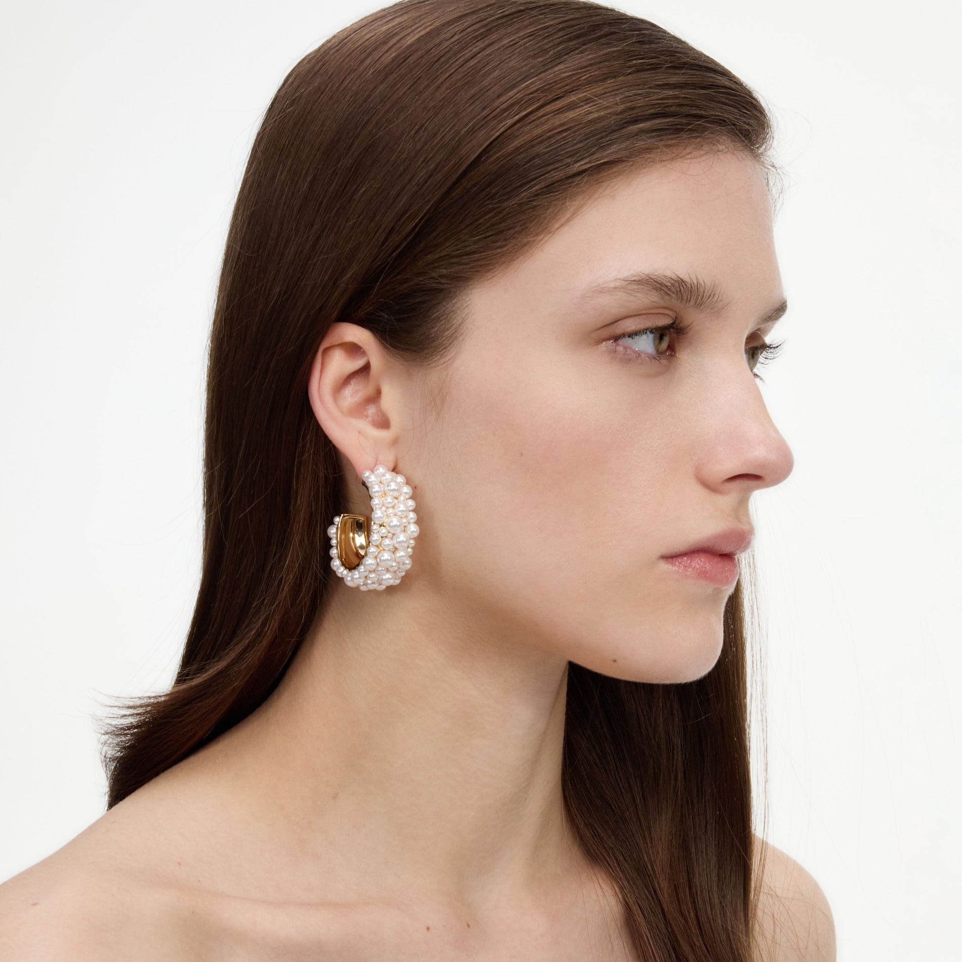 A close up of a woman wearing the Pearl Cluster Hoop Earrings