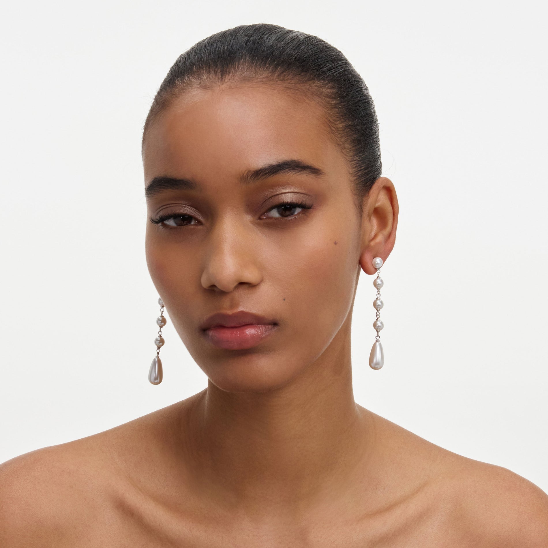 A close up of a woman wearing the Pearl Droplet Earrings