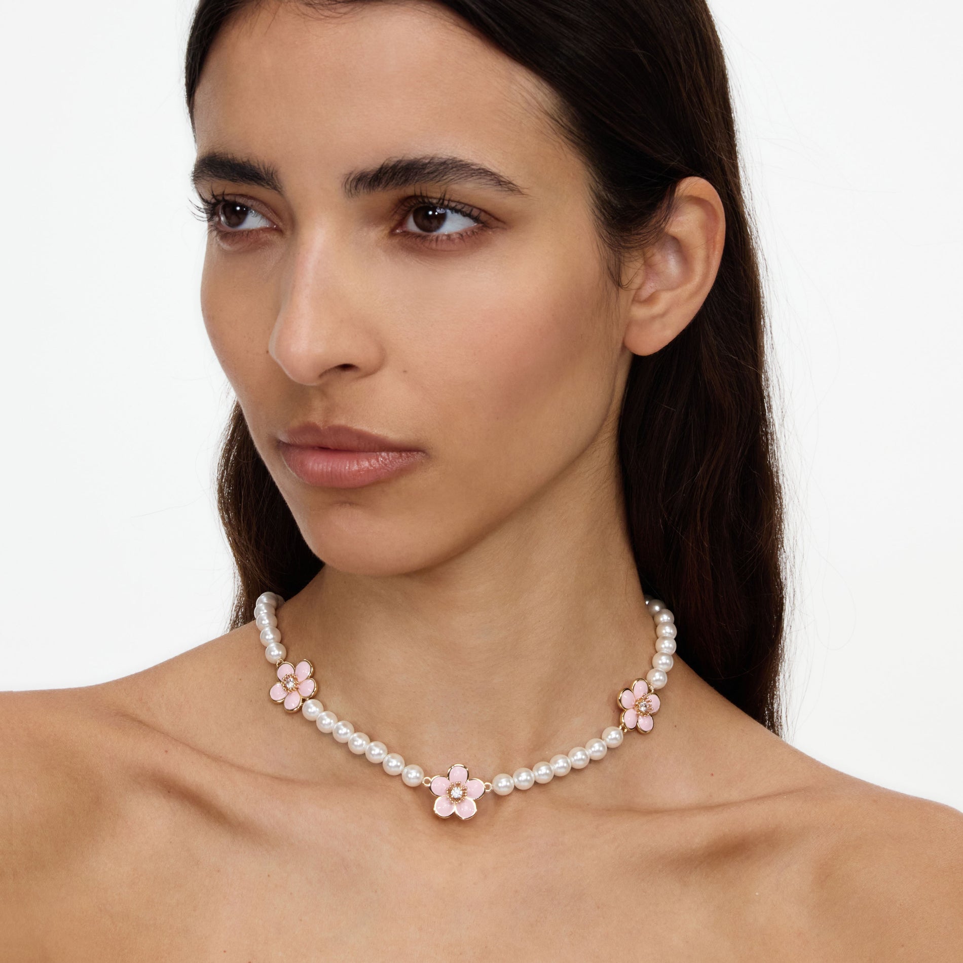 A close up of a woman wearing the Pink Enamel Flower Pearl Choker