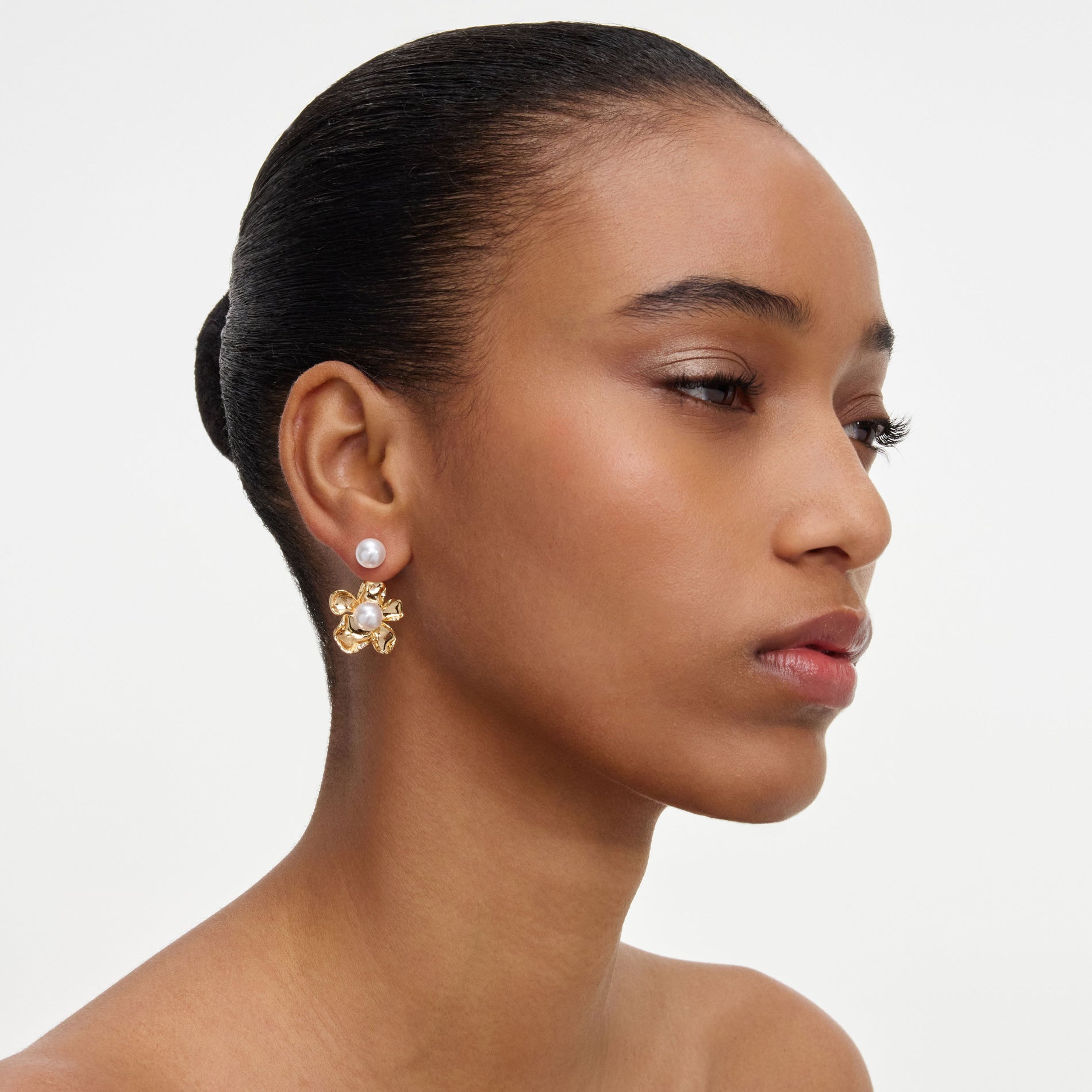 A close up of a woman wearing the Gold Flower Pearl Jacket Earrings