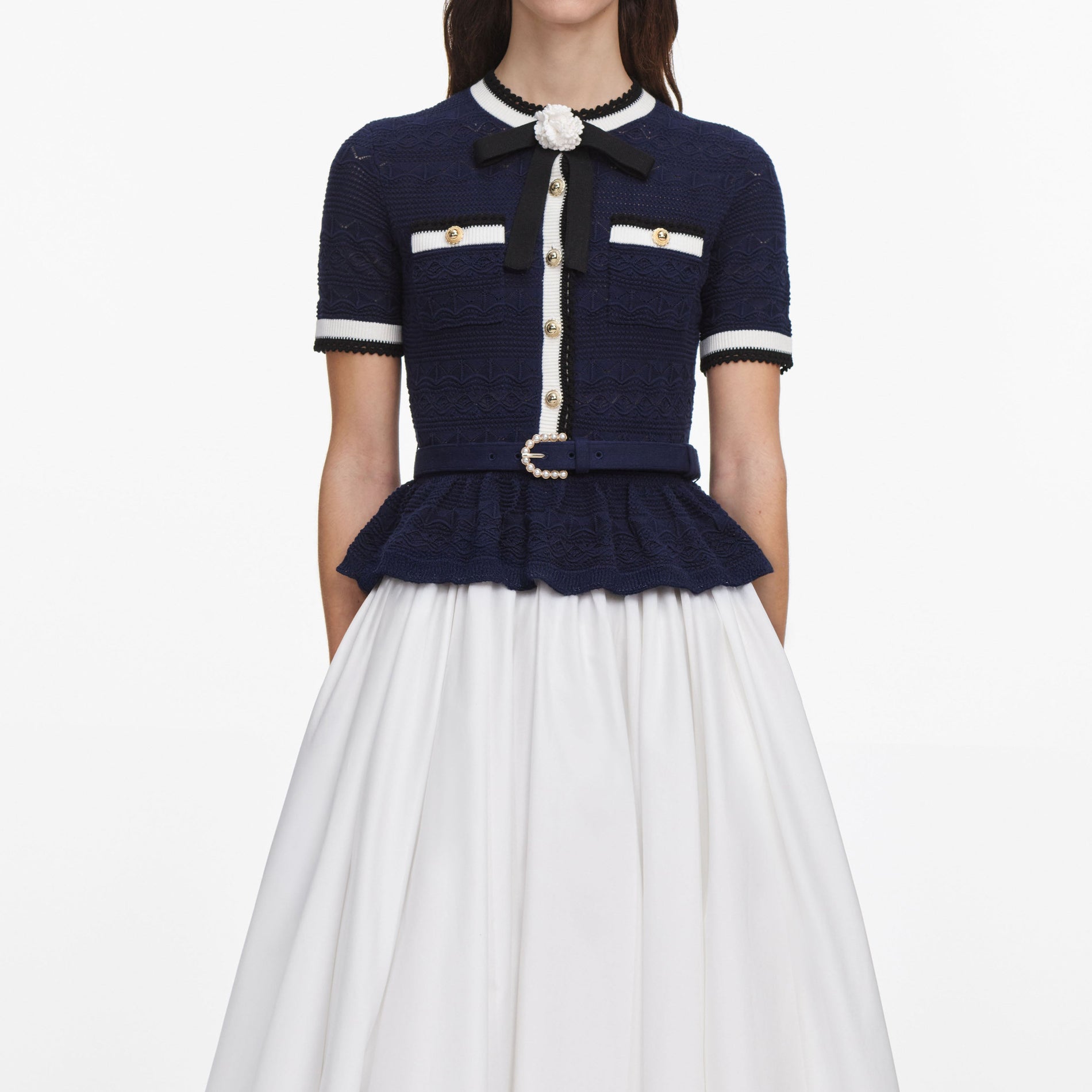 A close up of a woman wearing the Navy Peplum Pointelle Knit Top