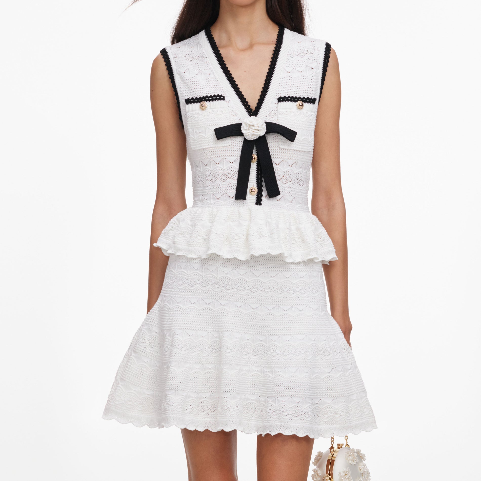 A close up of a woman wearing the White Peplum Pointelle Knit Mini Dress