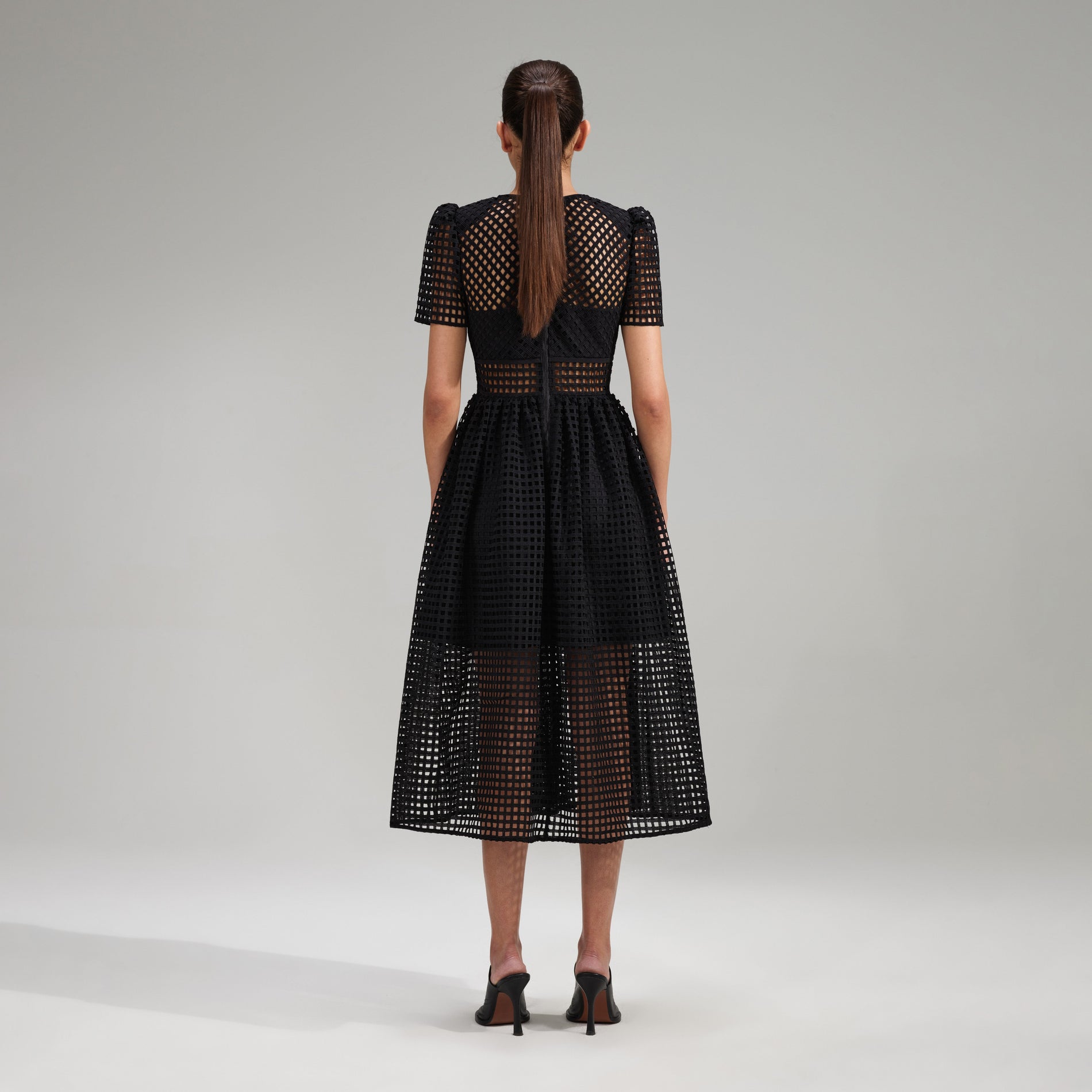 A woman wearing the Black Grid Lace Midi Dress