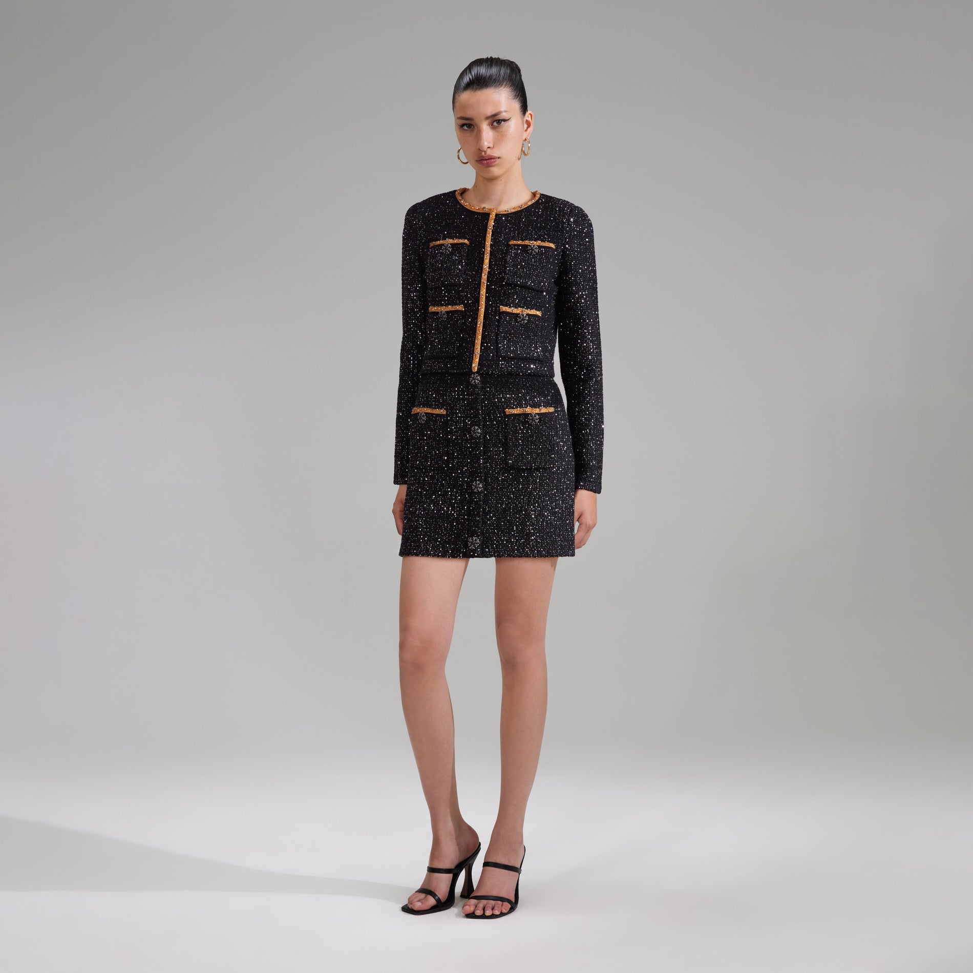 A woman wearing the Black Sequin Knit Mini Skirt