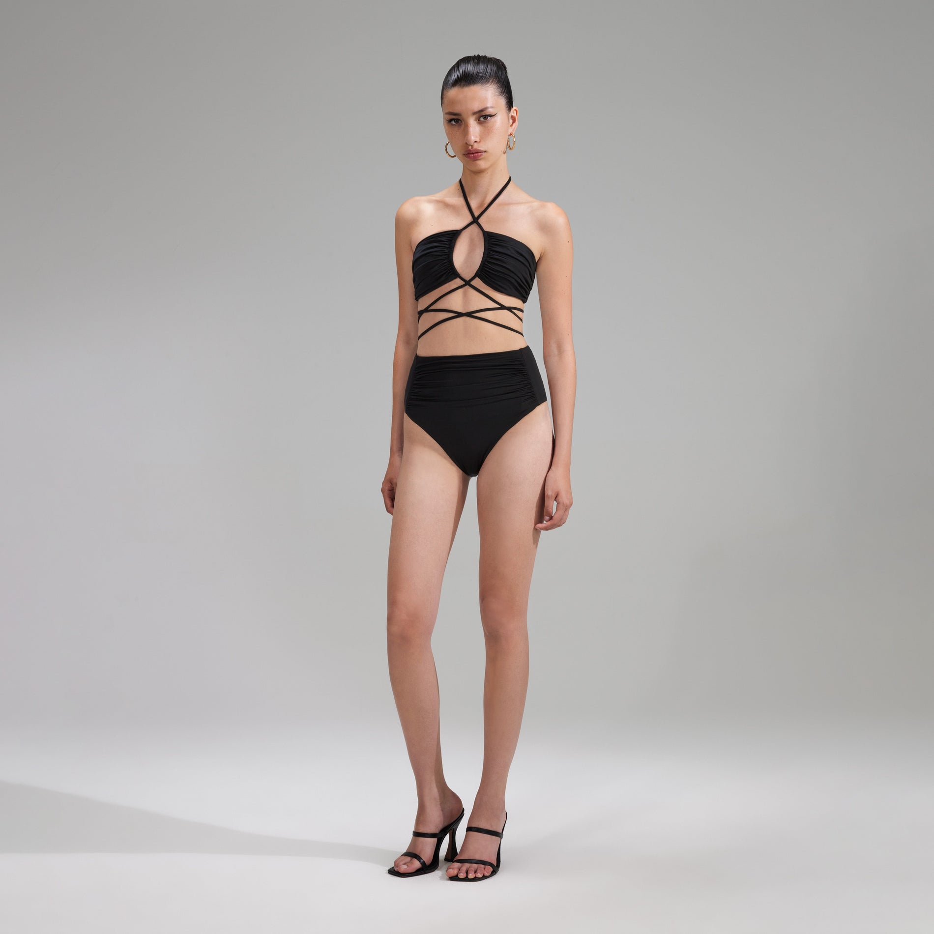 Side view of a woman wearing the Black High Cut Bikini Brief