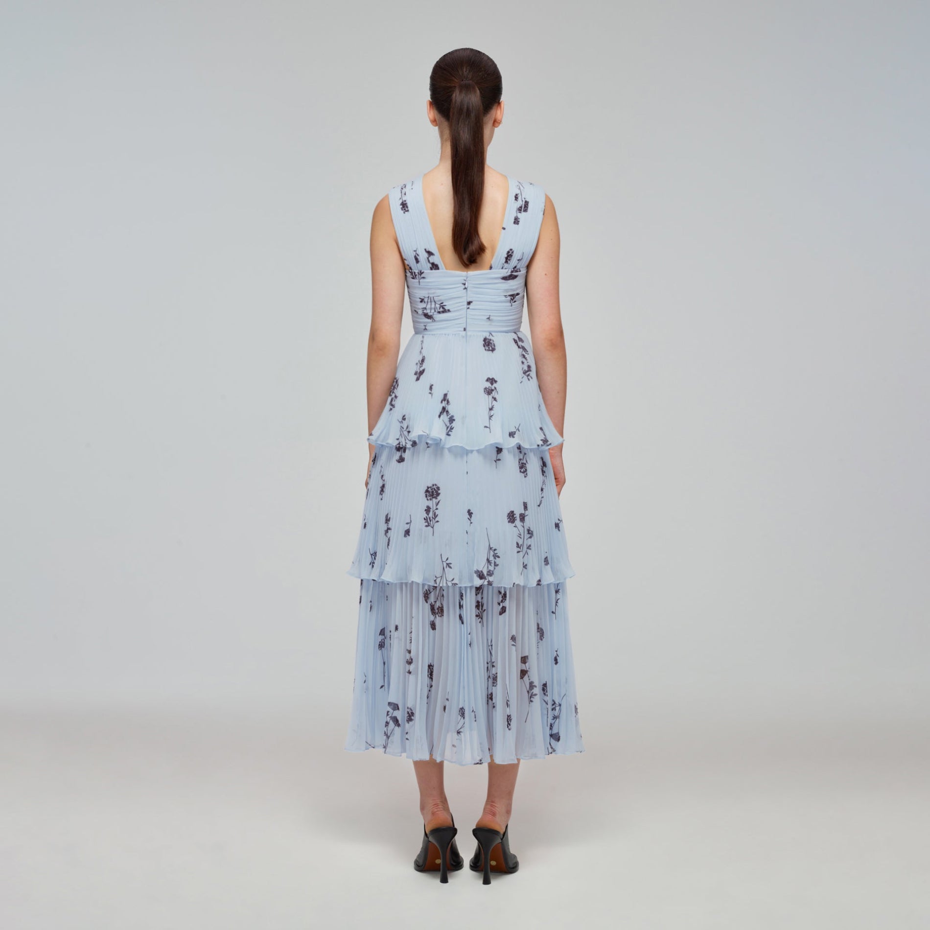 A woman wearing the Blue Floral Silhouette Chiffon Crossover Midi Dress