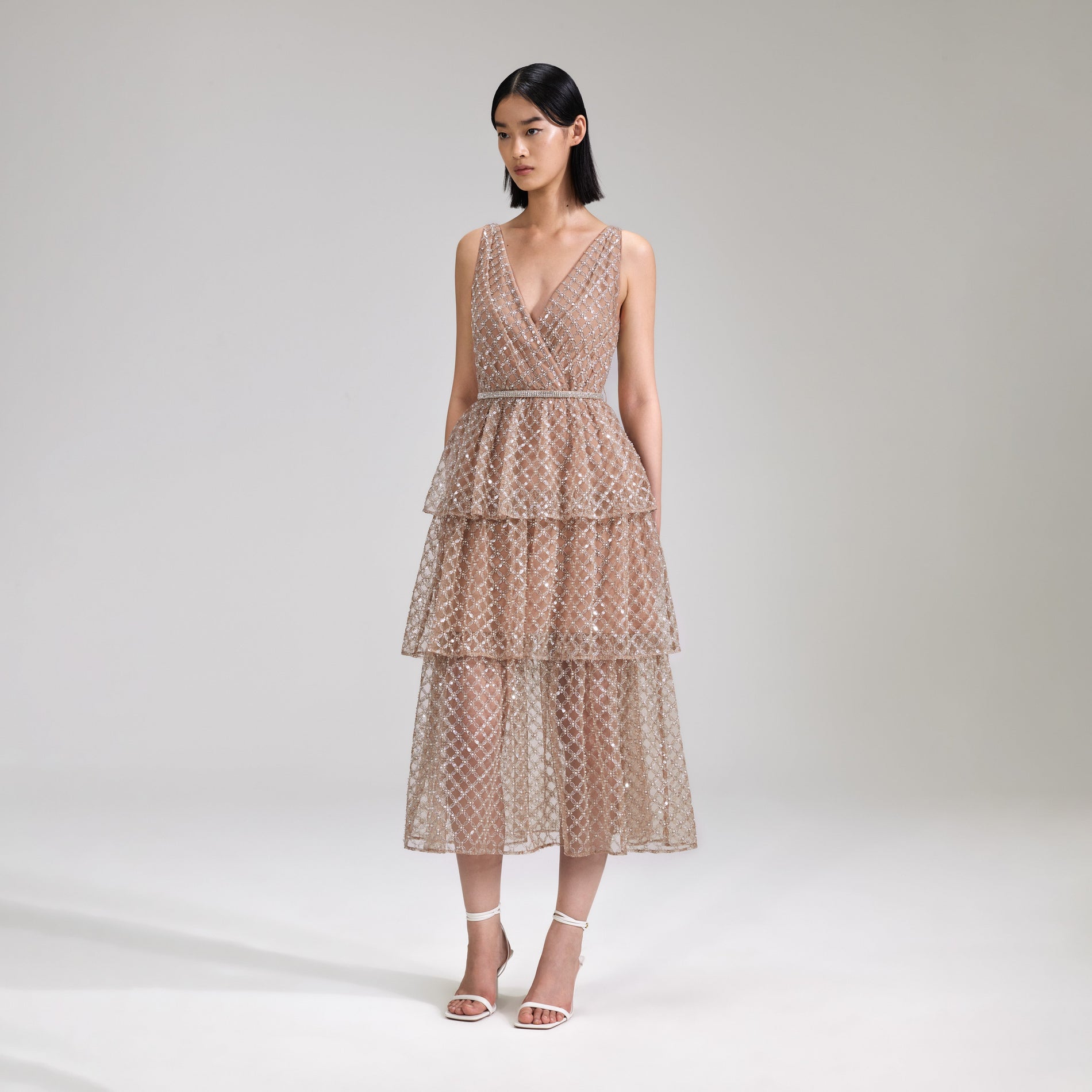 A woman wearing the Tan Grid Sequin Tiered Midi Dress