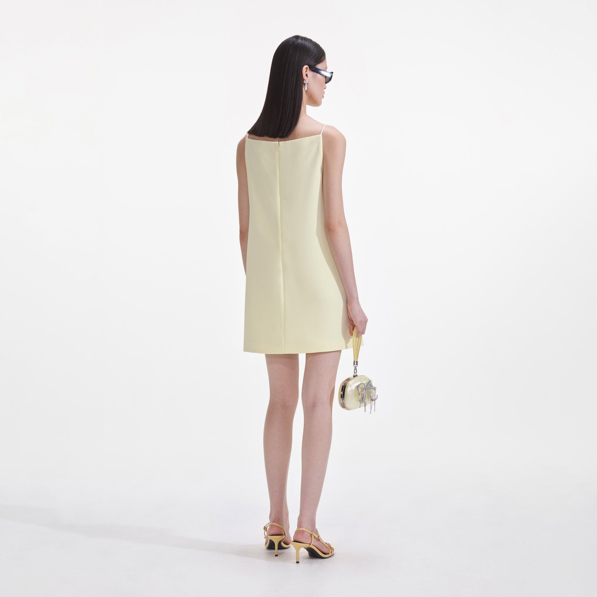 Back view of a woman wearing the Yellow Crepe Flower Mini Dress