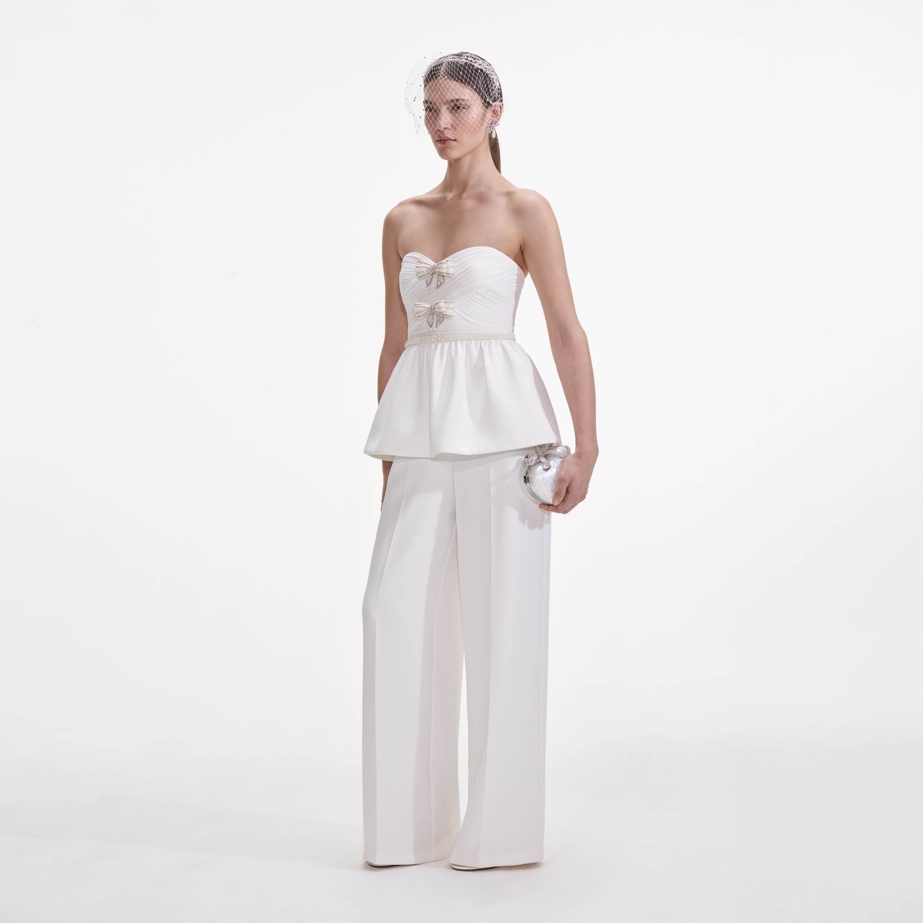 Side view of a woman wearing the White Organza Bow Jumpsuit