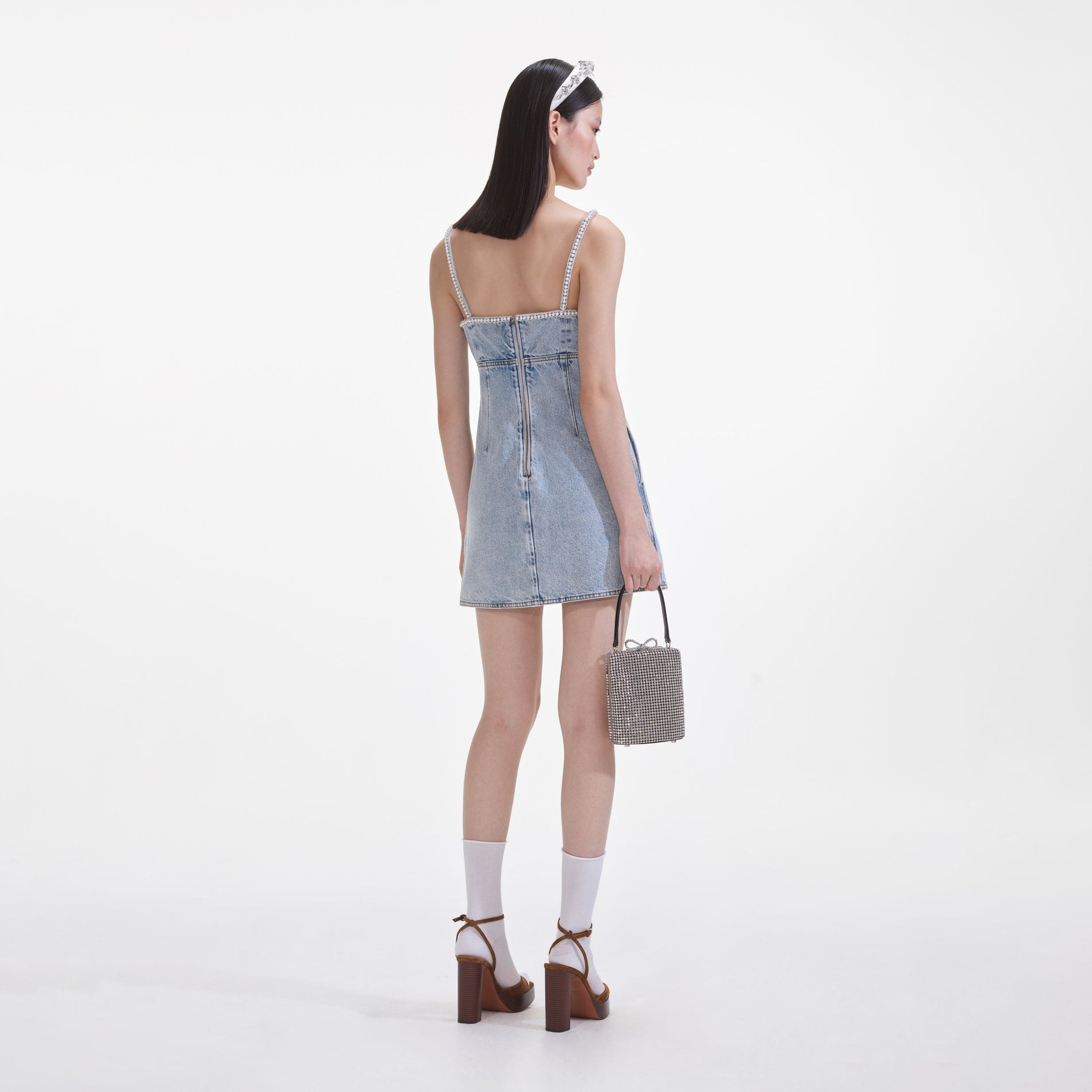 Back view of a woman wearing the Light Blue Denim Pearl Mini Dress