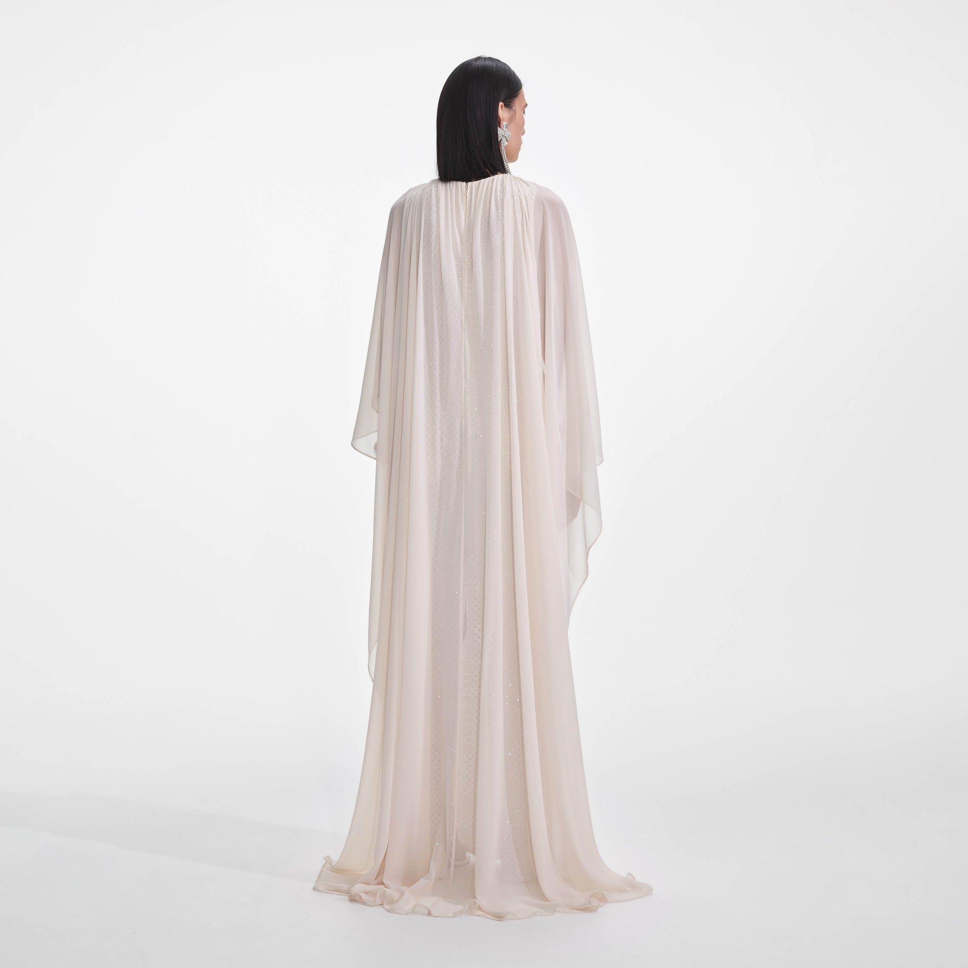 Back view of a woman wearing the Cream Rhinestone Cape Maxi Dress