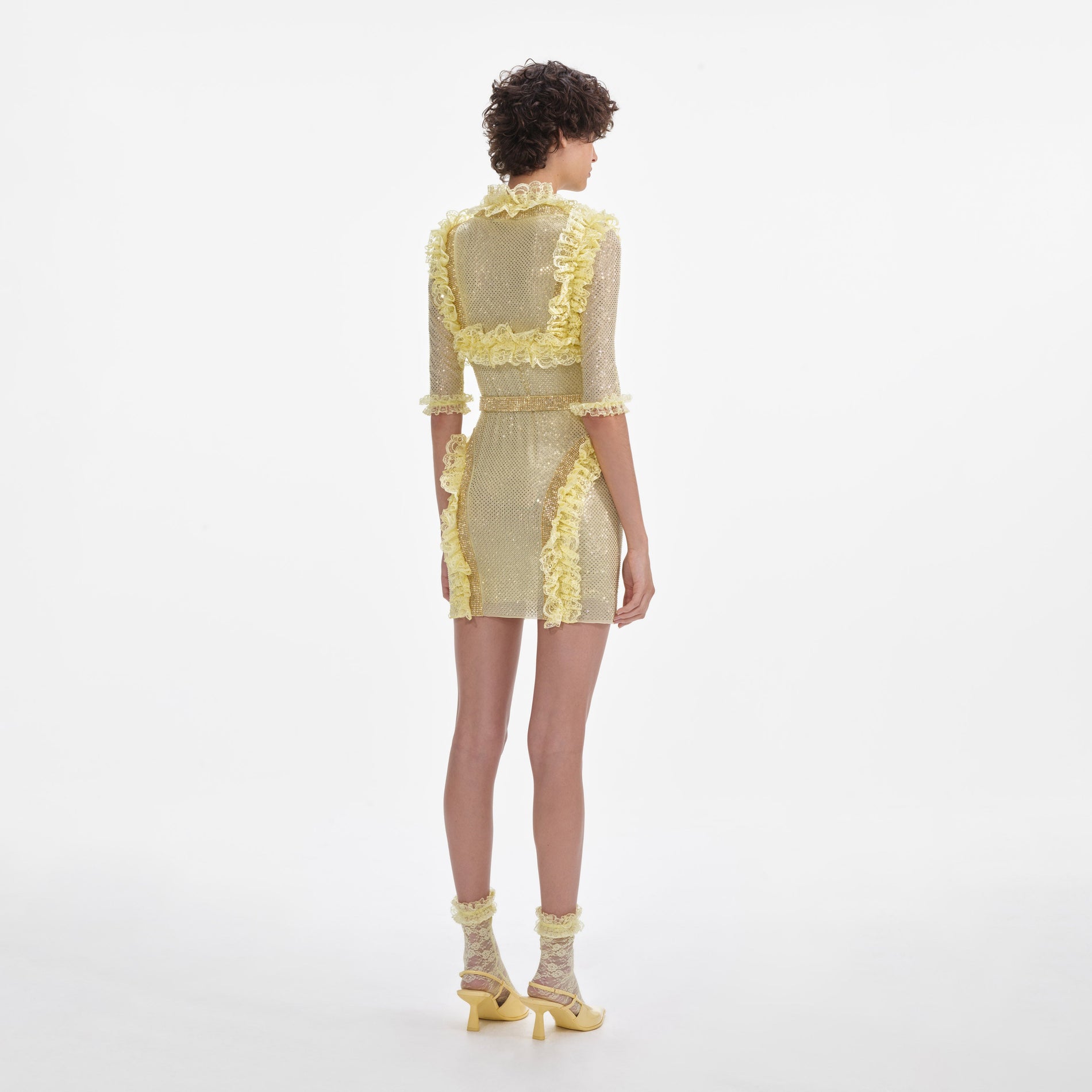 Back view of a woman wearing the Yellow Rhinestone Mesh Ruffle Mini Dress