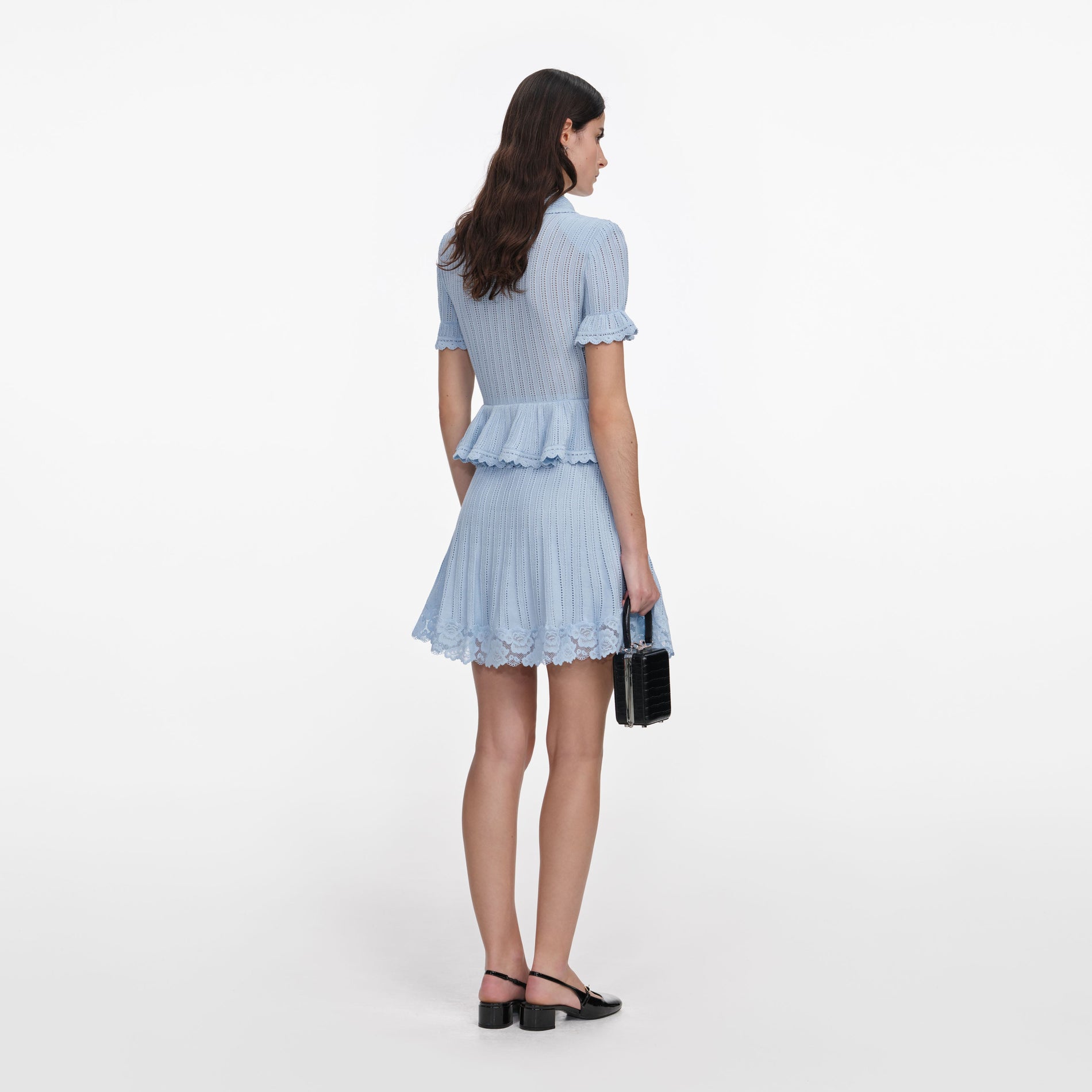 Back view of a woman wearing the Blue Pointelle Peplum Knit Mini Dress