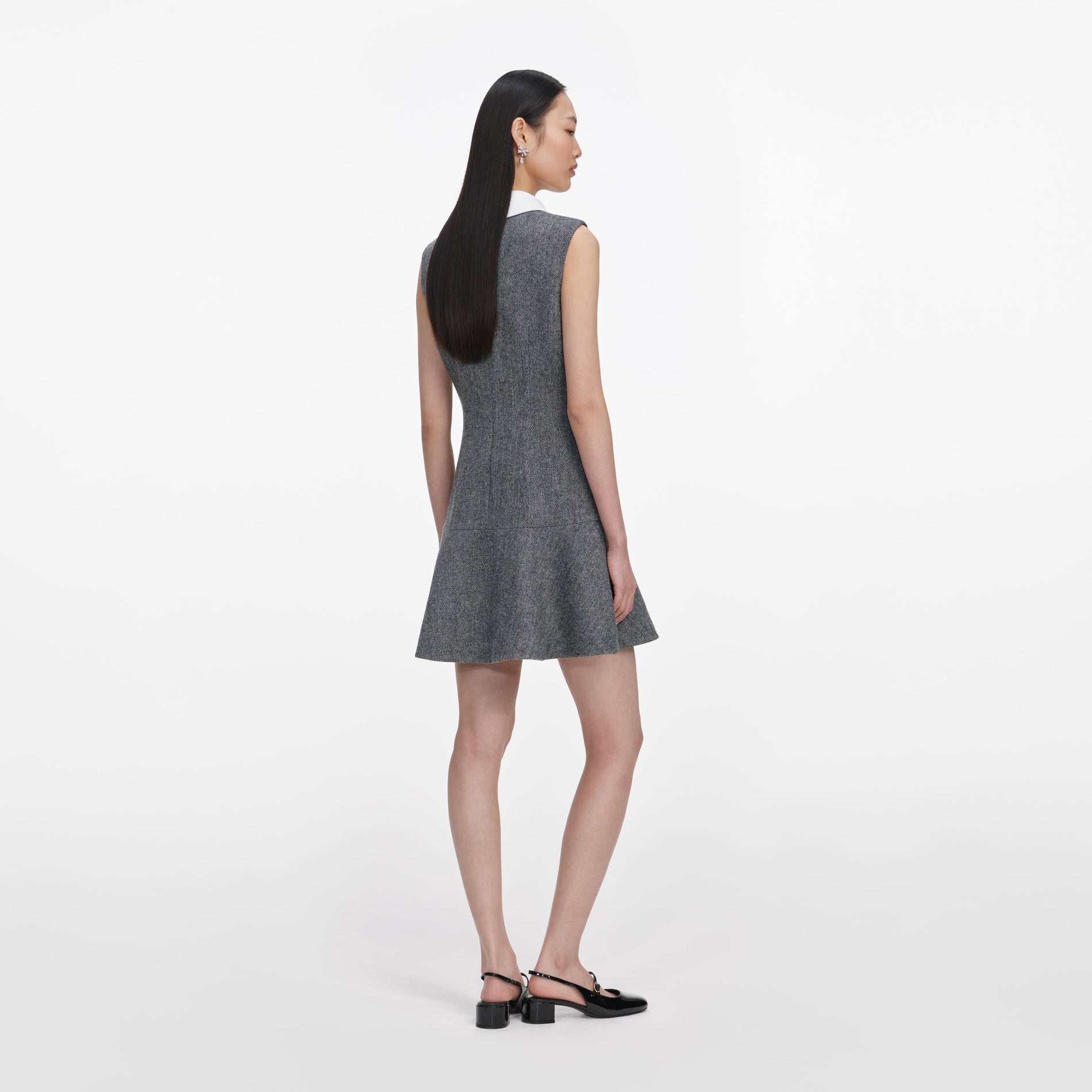 Back view of a woman wearing the Grey Herringbone Lace Bib Mini Dress